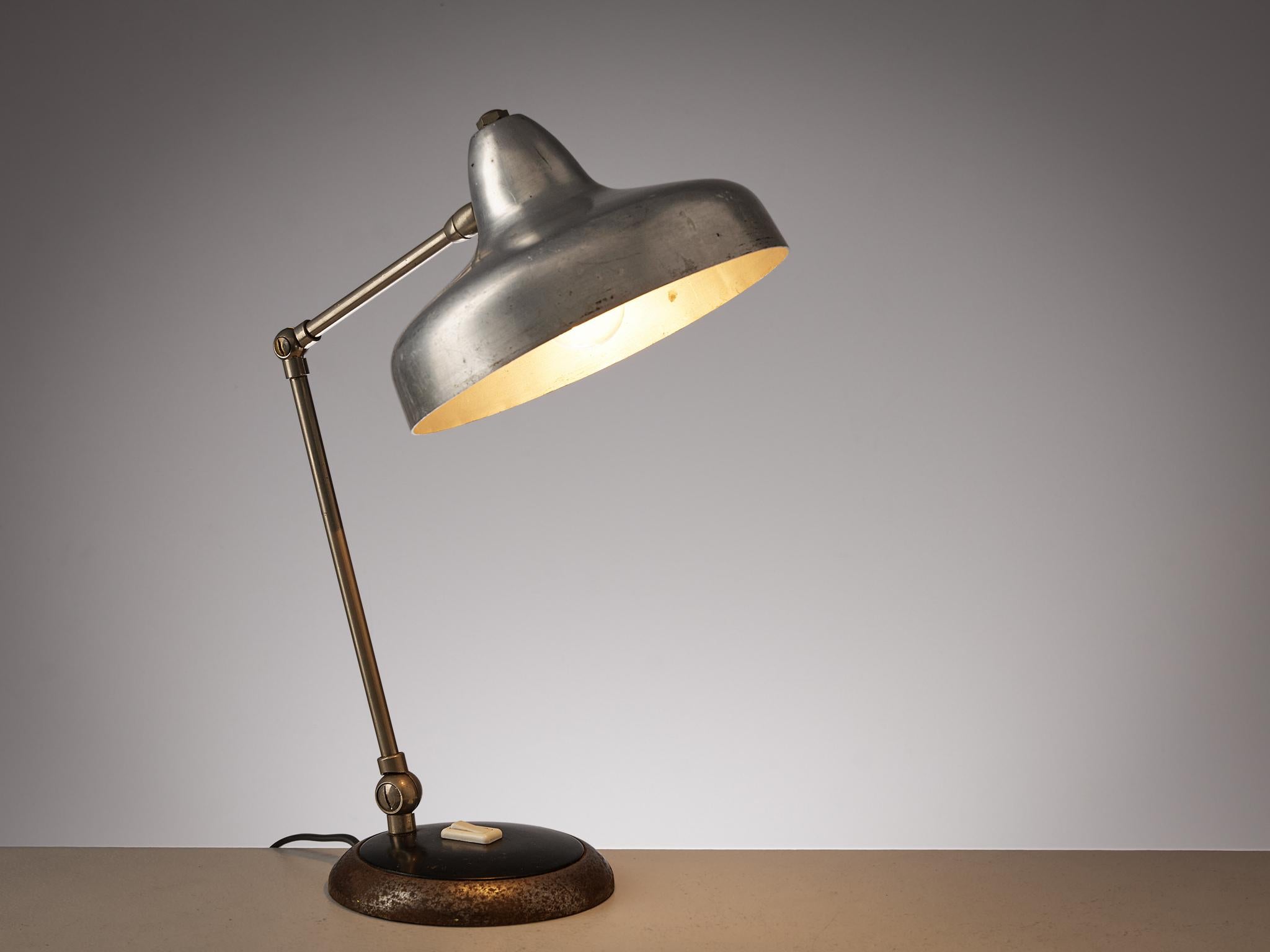 Table lamp, iron, brushed aluminum, Italy, 1950s

This small desk light combines functionality and visual pleasing design. From a round base in iron the adjustable stem with two arms is attached. At its end, a beautifully shaped lampshade that