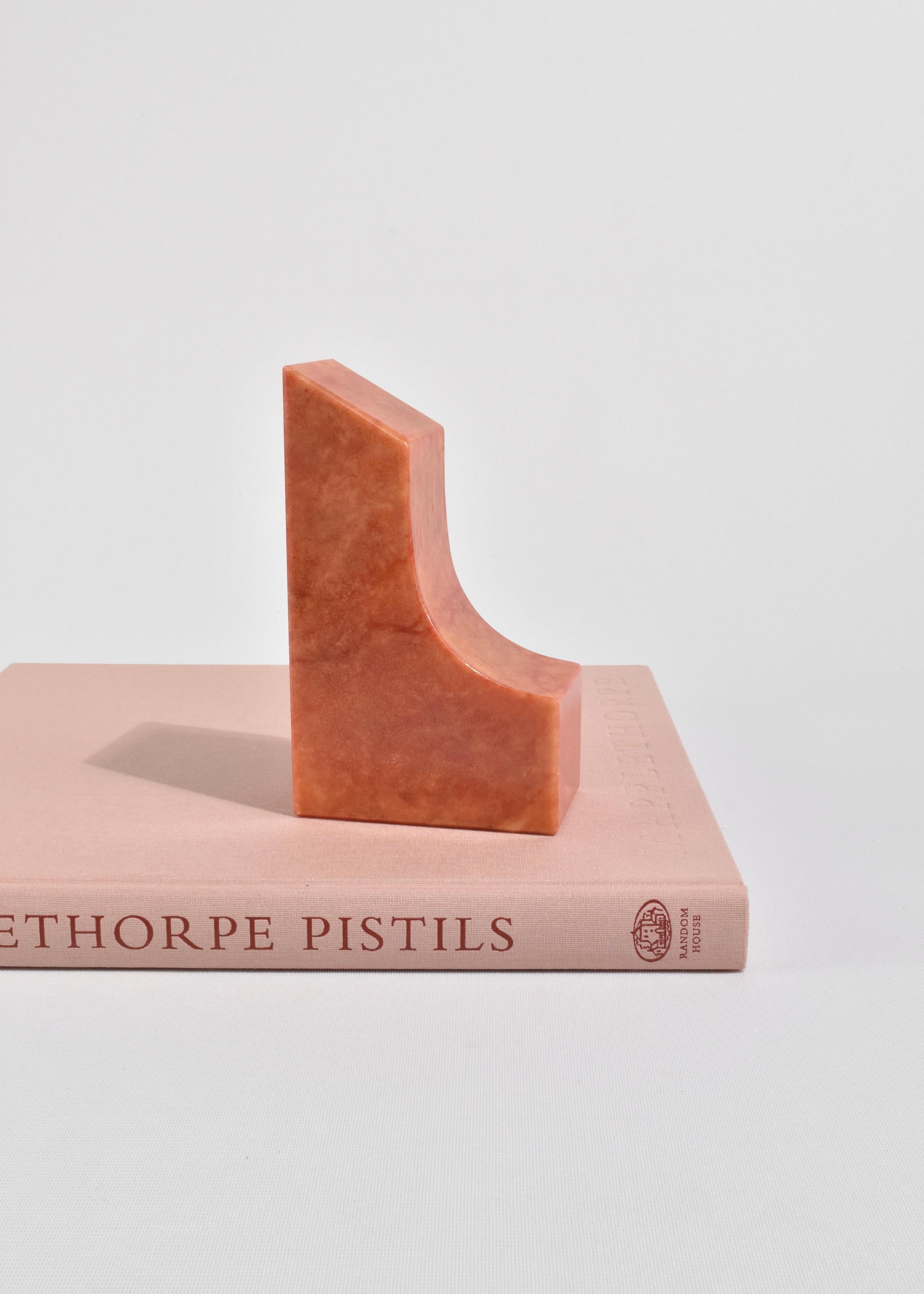 Beautiful, carved coral colored alabaster bookends in a curved shape. A sticker on the base reads, Genuine Alabaster Hand Carved, Made in Italy.