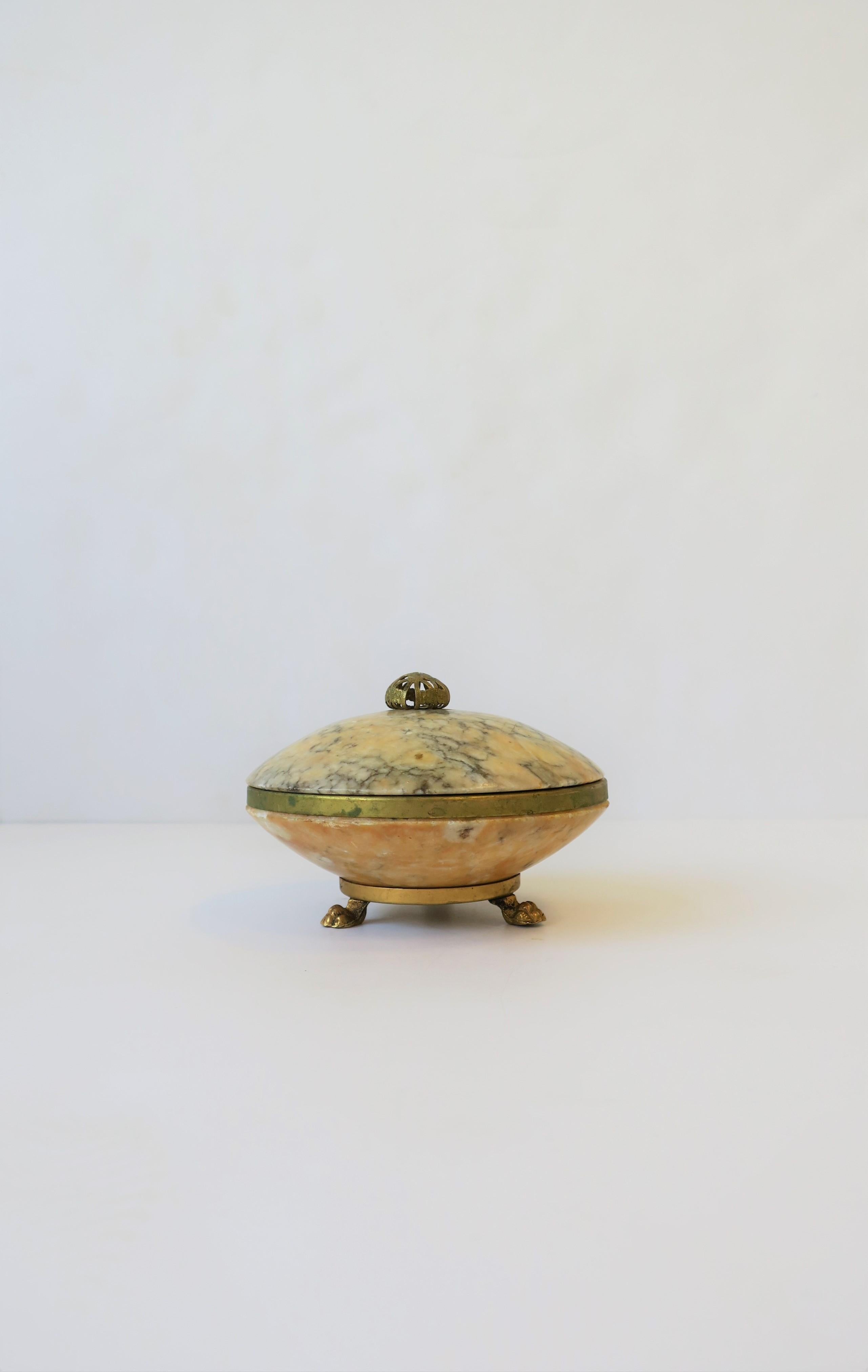 An Italian alabaster marble and brass round box in the neoclassical style, circa mid-20th century, Italy. Box has brass detailed top, brass band and three brass paw feet. A beautiful standalone piece, for jewelry (as demonstrated), or other items on