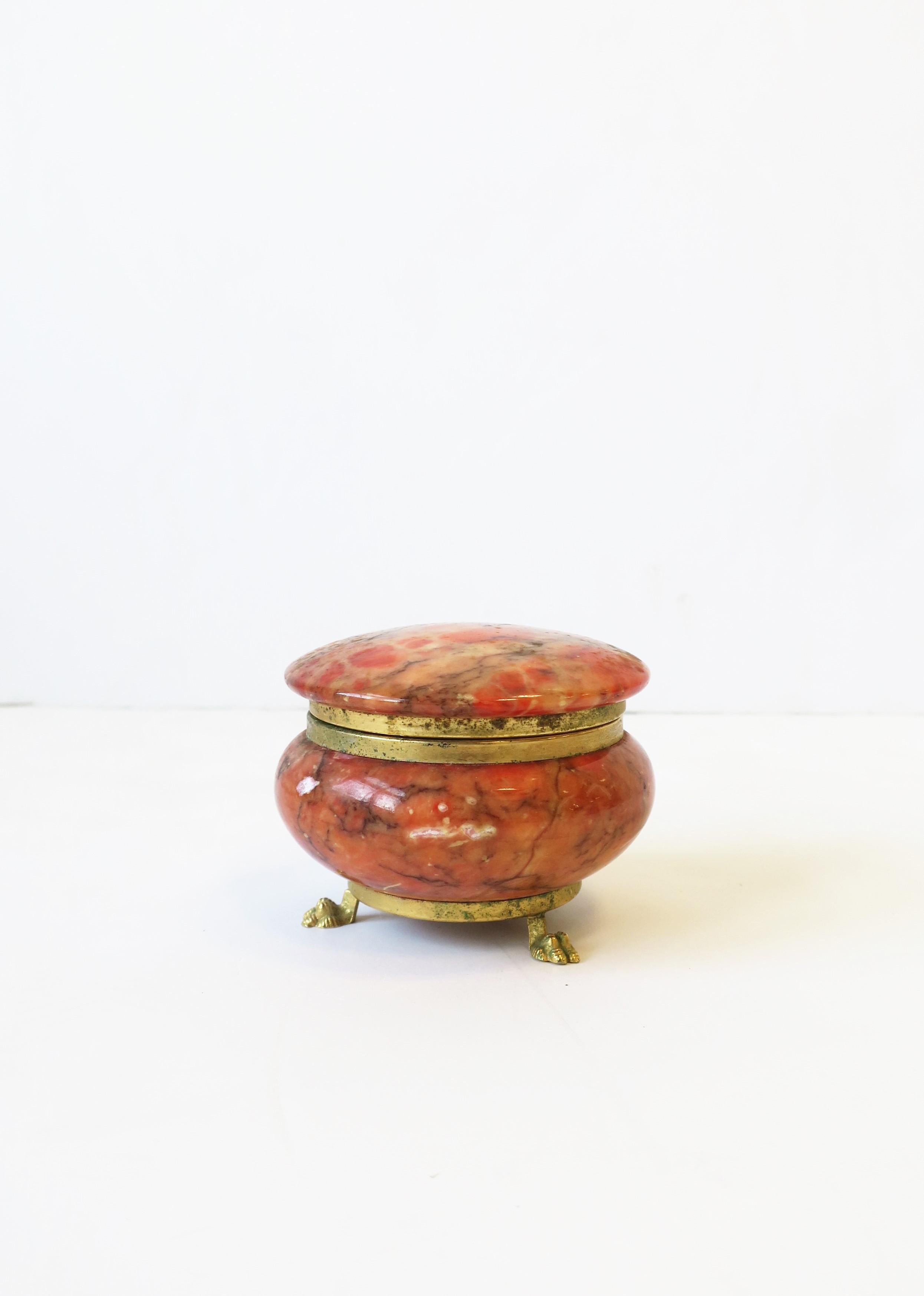 A mid-20th century Italian alabaster marble and brass round jewelry box in the Empire style, Italy. Alabaster marble is a combination of coral and pink hues, with brass hinge and paw base. A useful piece for jewelry (as demonstrated), or other small