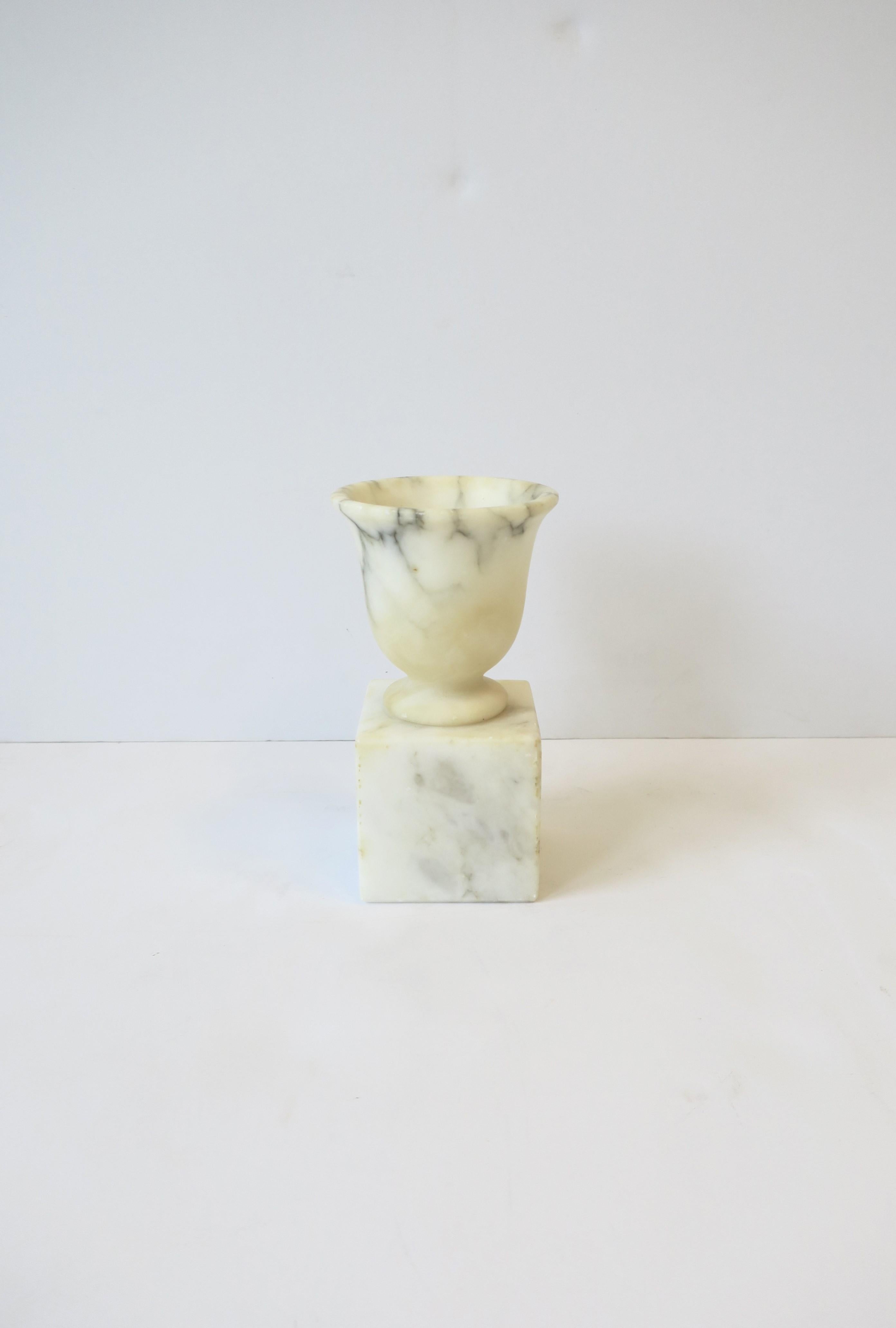 An Italian alabaster marble urn on pedestal base in the Neoclassical style, circa early to mid-20th century, Italy. 
This decorative object is made from one piece of alabaster marble. Beautiful as a standalone piece or blended with other items (as