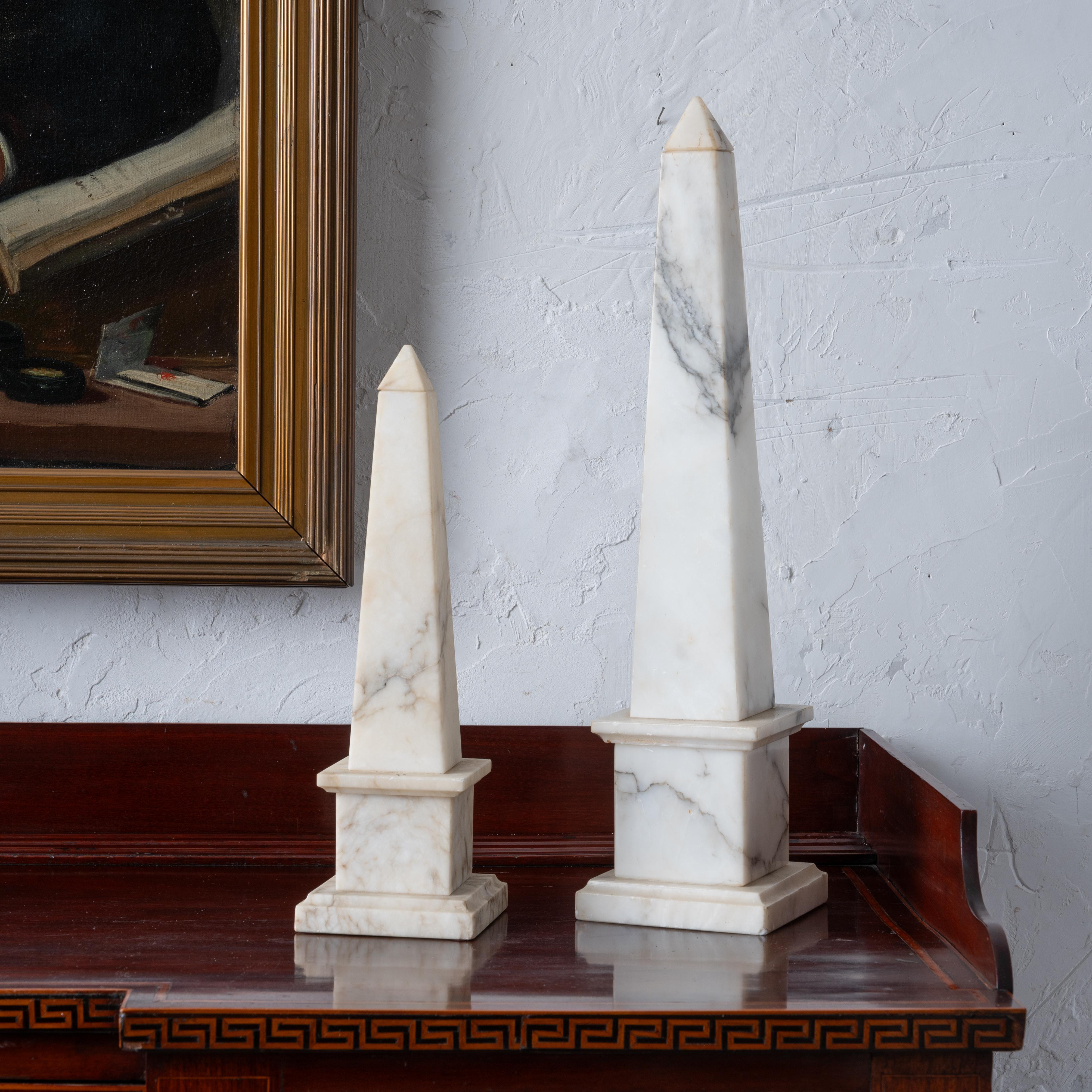 A pair of Italian alabaster obelisks, mid 20th century. With removable caps and drilled for lamp conversion.

larger: 5 inches wide by 20 inches tall 
smaller: 4 ¼ inches wide by 14 inches tall