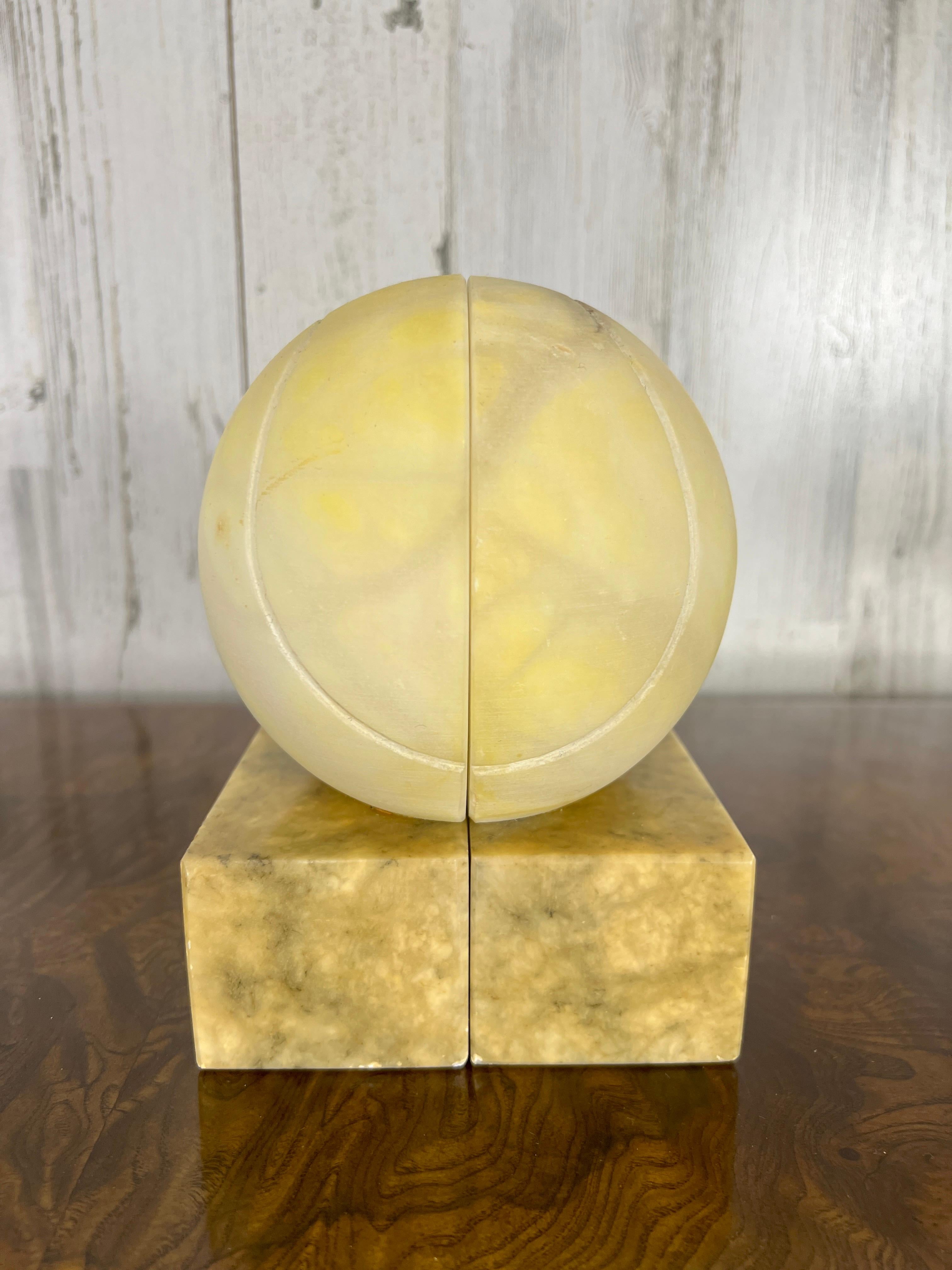 Solid alabaster carved into tennis ball design that can be used as a sculpture or book ends.