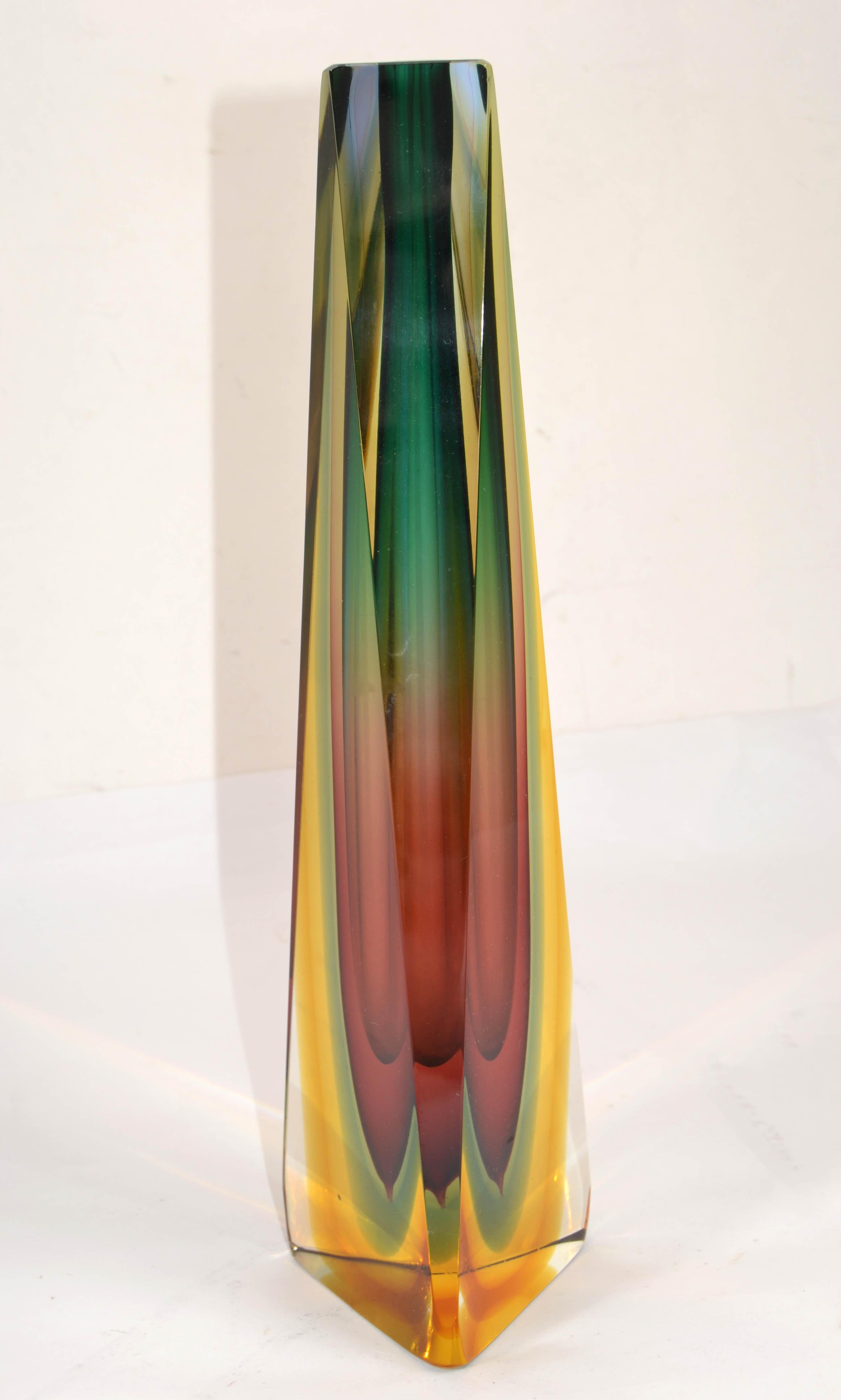 Superbe vase italien en verre d'art de Murano soufflé et facetté, datant du milieu du siècle dernier, en verre ambre, vert, bleu et transparent, attribué à Alessandro Mandruzzato, vers 1970.
Cuve triangulaire biseautée avec couvercle poli.
Reflète