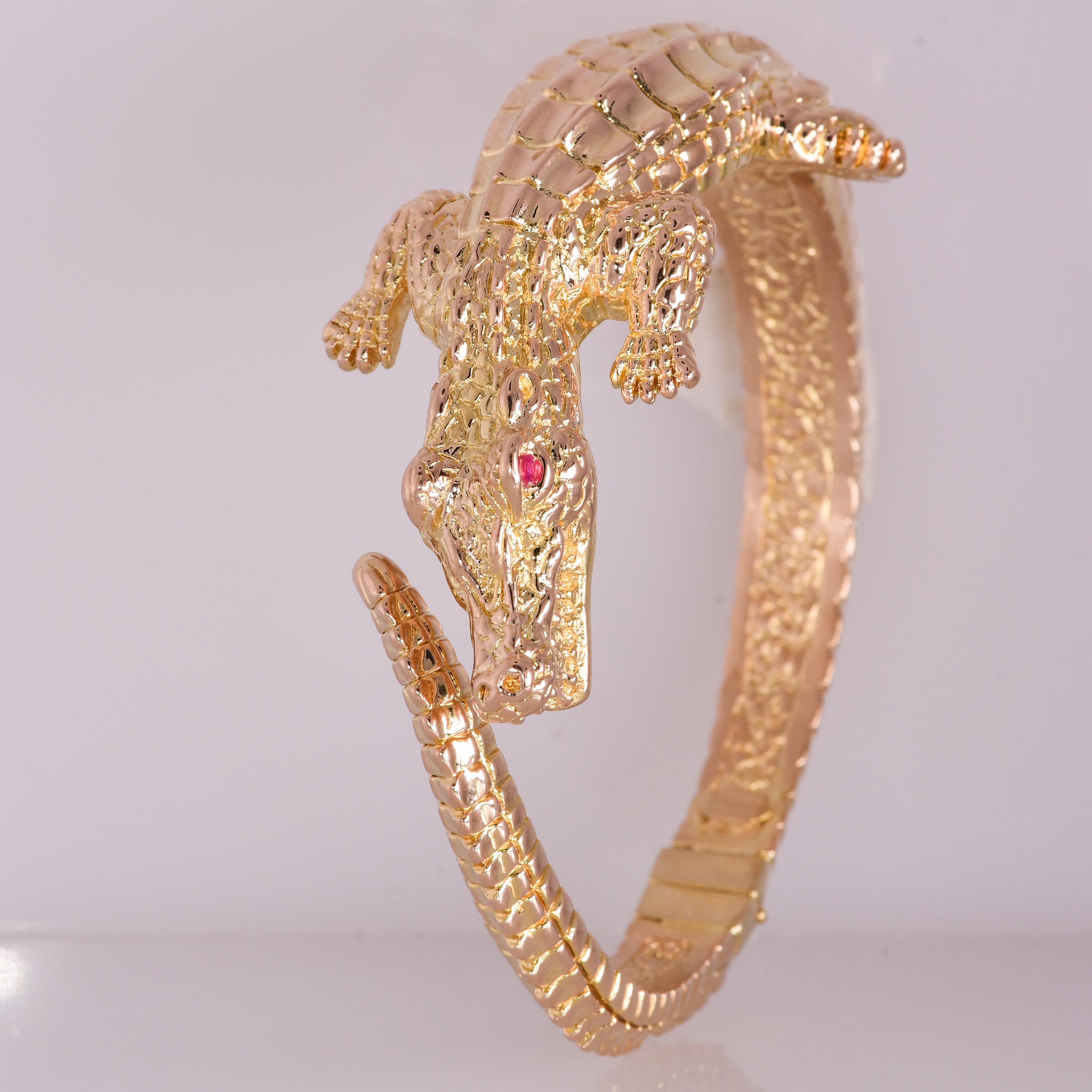 The wild side of Italian gold. Using a unique process called electroforming, goldsmiths craft this textured alligator bangle bracelet to have a bold look and a comfortable feel on the wrist. Hinged, 14kt yellow gold alligator bracelet. Natural ruby