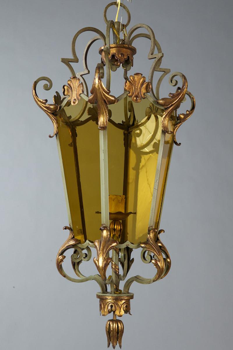 Circa 1920s Italian lantern style pendant has a pale green iron frame embellished with gilt metal acanthus leaf and fan details. Lantern features six amber colored glass panels surrounding a single standard sized socket. Rewired for US electrical