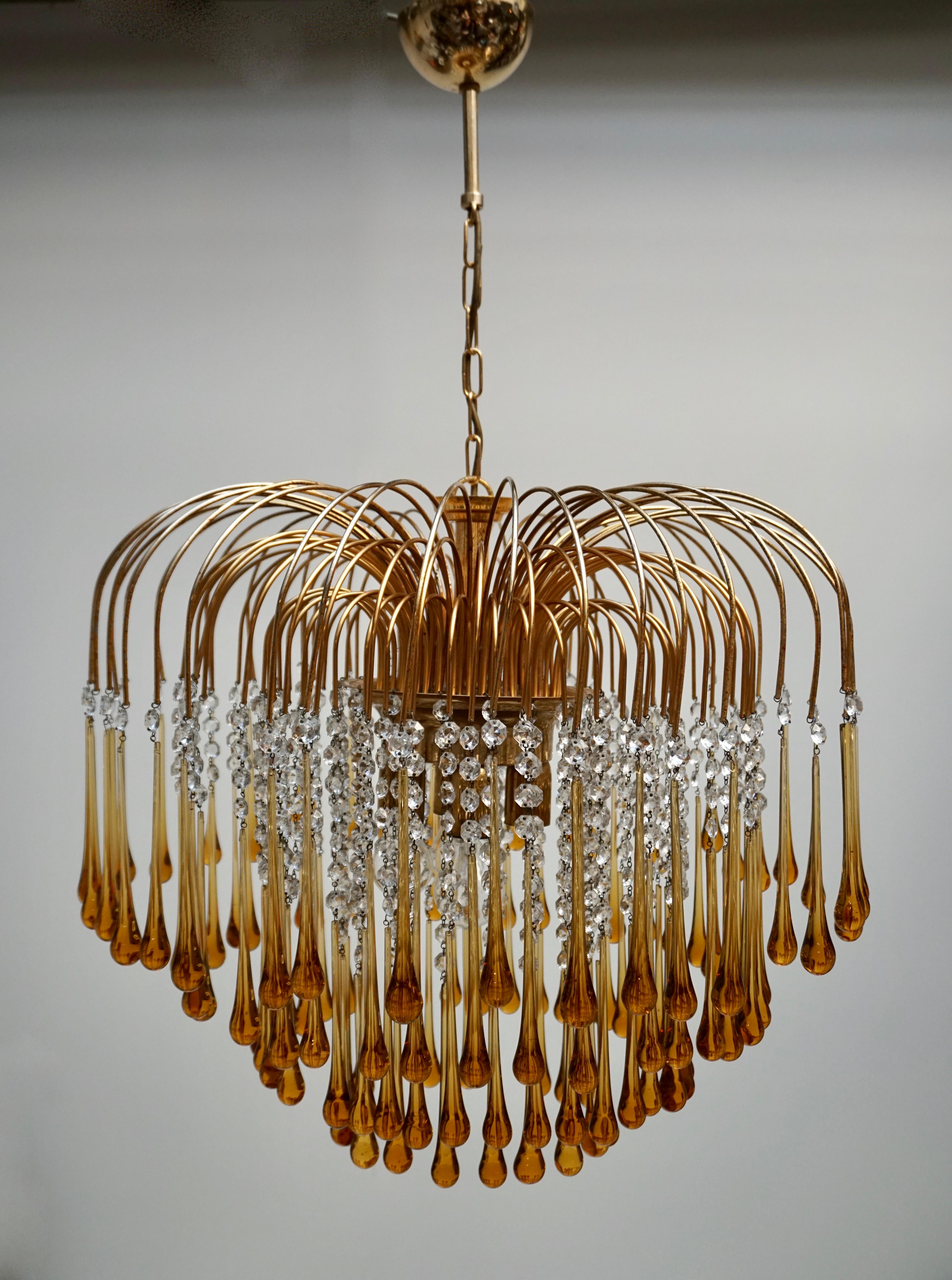 Elegant large brass and amber Murano crystal chandelier by Venini.

The lamp is decorated with hand blown amber crystal Murano teardrop glasses. 

The chandelier emits a stunning light. 

The lamp is fitted with four E27 light sockets. It comes with