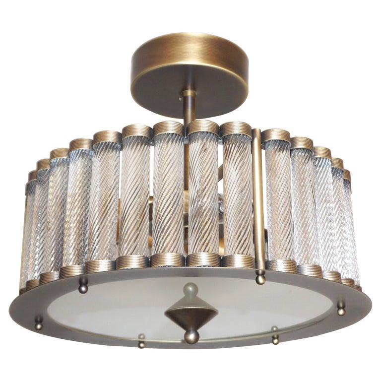 Contemporary Italian Art Deco Design customizable round chandelier/pendant of drum shape, entirely handcrafted, with an antique bronze finish. The nicely scalloped airy brass structure supports crystal clear Murano glass rods worked with the