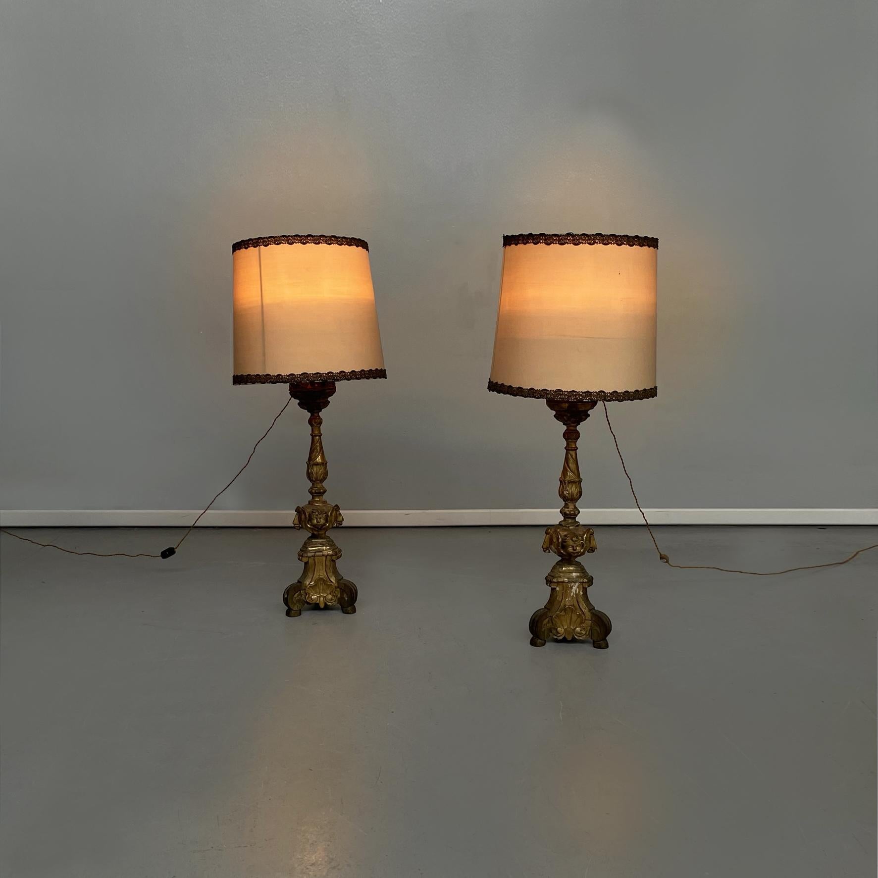 Lampes candélabres italiennes anciennes en bois peint en or et tissu beige, années 1800
Paire de lampes candélabres en bois peint en or. L'abat-jour est en tissu beige avec des garnitures en fil d'argent. La structure en bois est finement