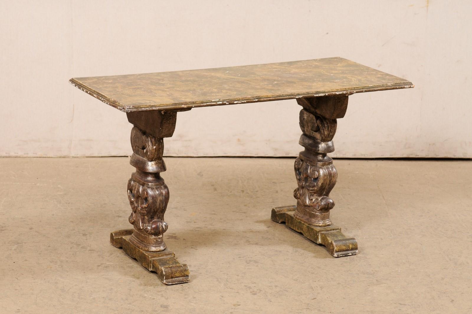 An Italian carved and painted wood coffee table from the turn of the 19th and 20th century. This antique table from Italy has a rectangular-shaped top, which is raised upon a pair of trestle style legs. Each leg is beautifully carved with volute and