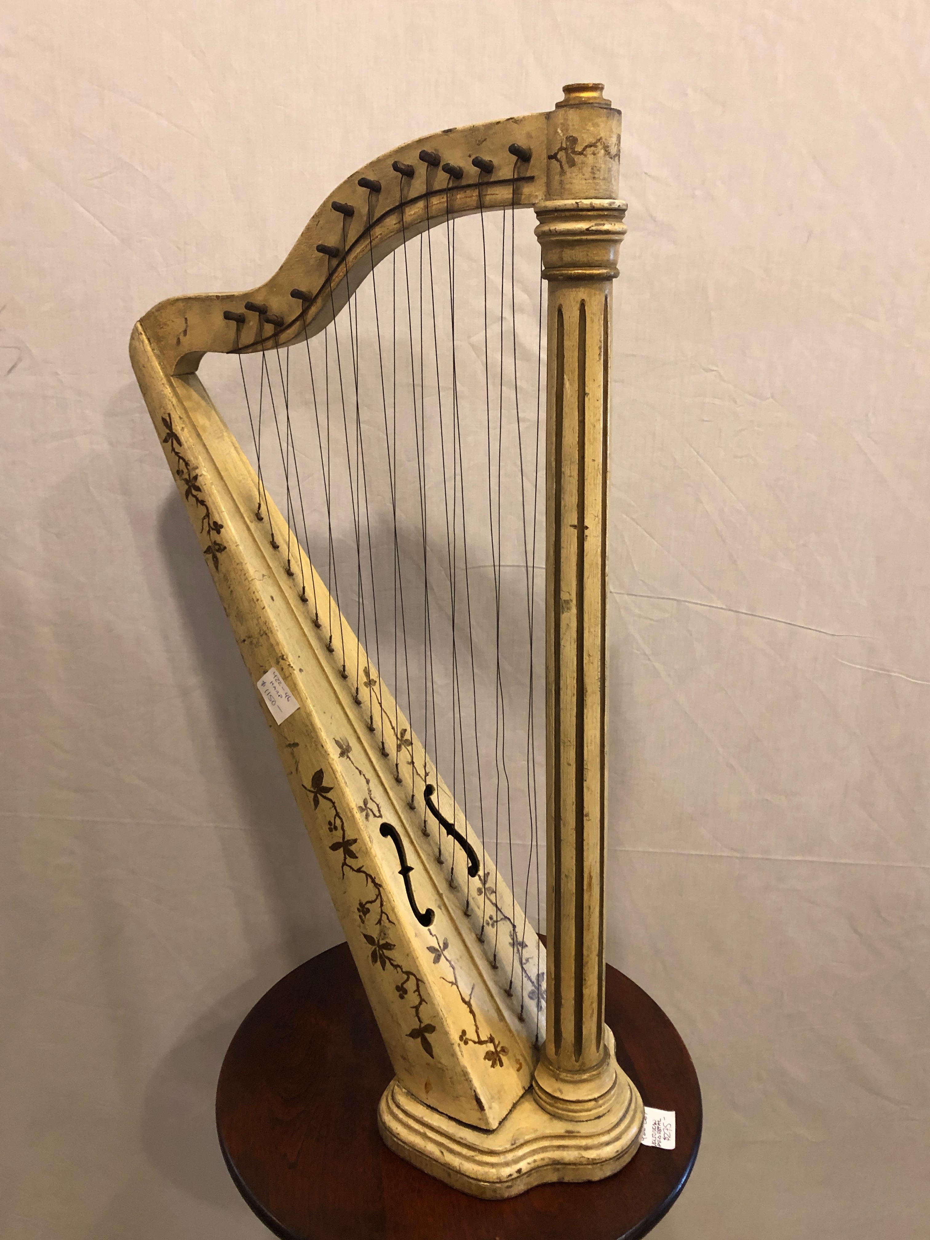 An Italian antique double string paint decorated table harp. This shining example of musicality is certain to draw attention and spark a conversation. Gilt gold decorated over a worn aged painted finish. Would need to be restrung to be played.