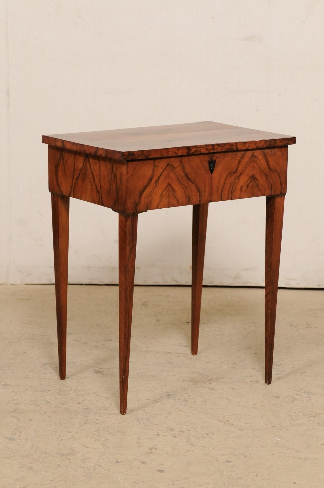 An Italian end table with book-matching walnut veneer from the late 19th to early 20th century. This antique side table from Italy features a beautiful book-match veneer on it's top and apron. The piece is otherwise minimally adorn, allowing the
