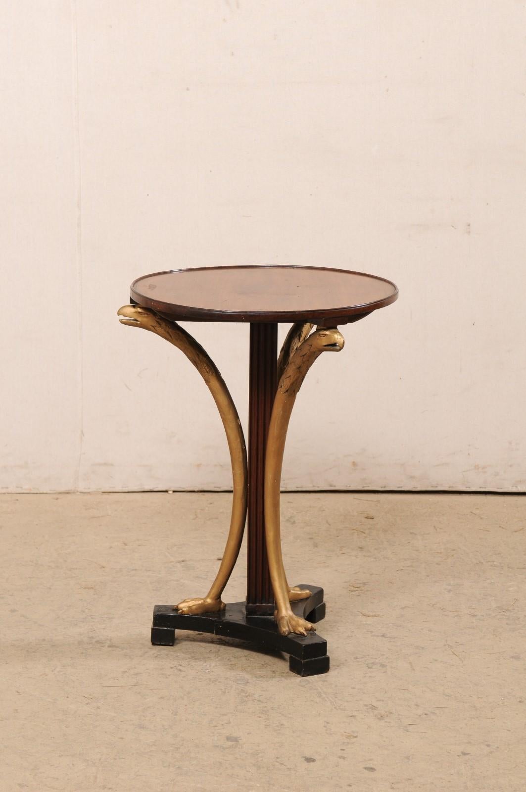 An Italian round side table with eagle accents from the 19th century. This antique gueridon table from Italy has a round-shaped top with a thin, raised lip along its edge, which is supported on a squared and fluted column, and raised on a black