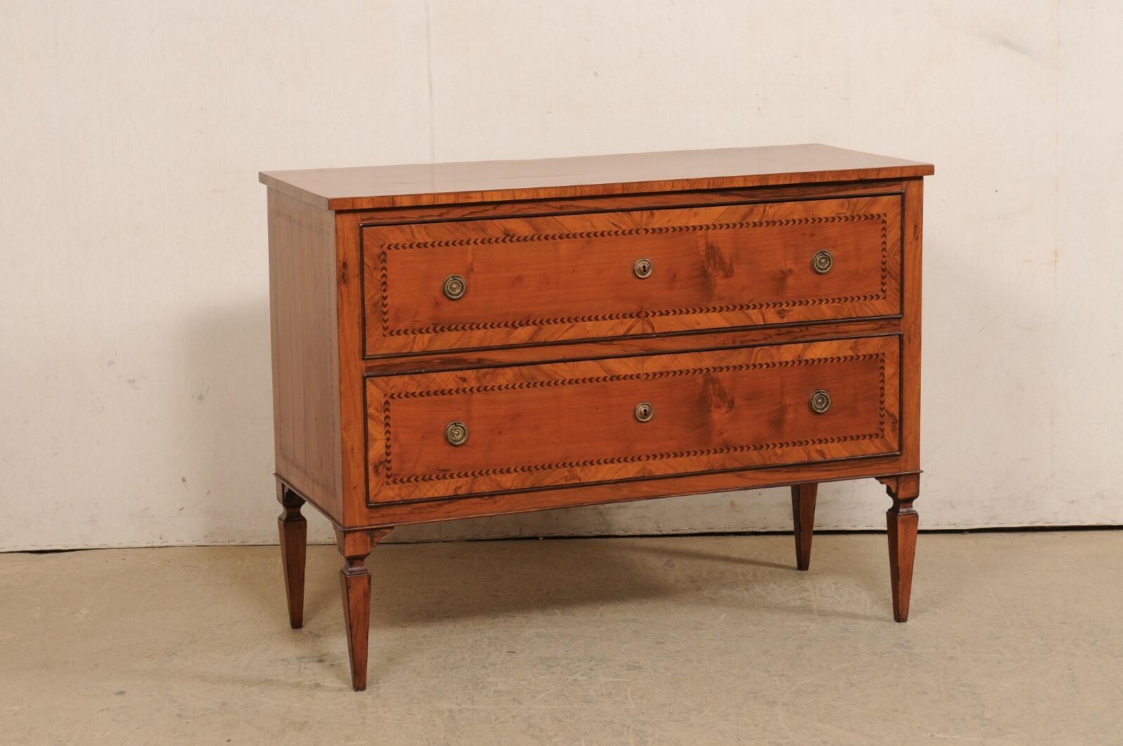 An Italian two-drawer chest with inlay accents from the 19th century. This beautiful antique fruitwood chest from Italy features delicate inlay banding that outlines the perimeter about the top, drawer fronts, and each side. The rectangular-shaped