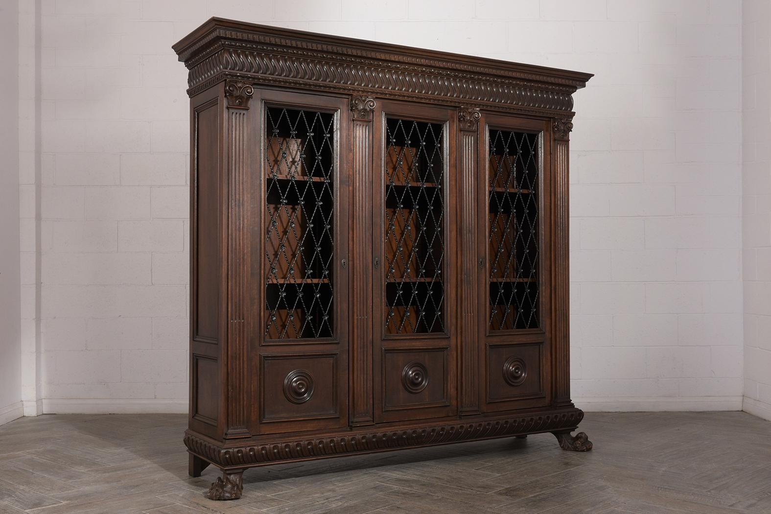 This 1900s Italian Renaissance bookcase has been professionally restored, is made out of walnut wood, and stained in a rich dark walnut color with a beautiful patina finish. This antique triple door bookcase features finely hand-carved details