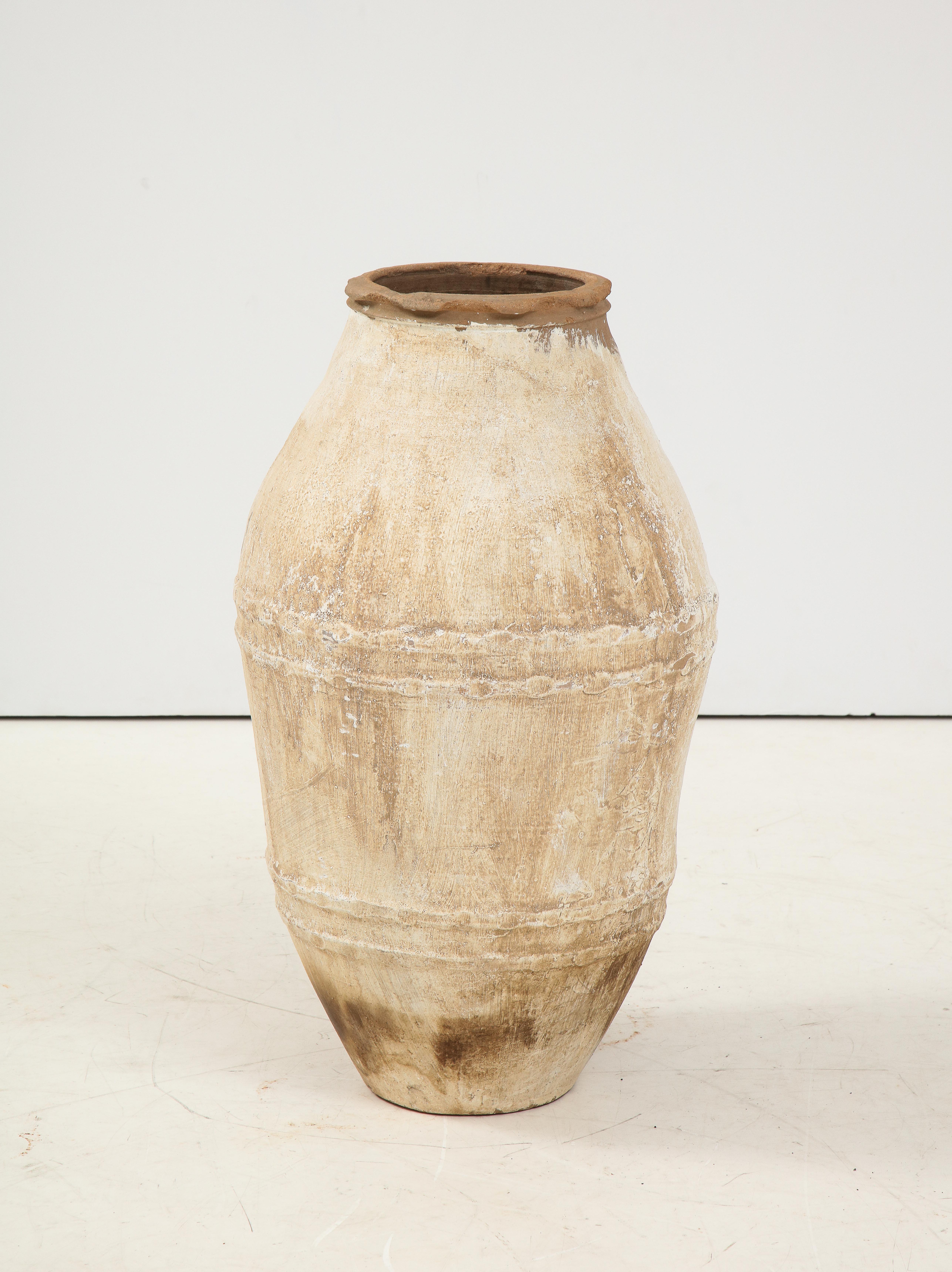 An Italian antique terracotta olive oil jar in white painted finish; with a beautifully aged patina and the natural terracotta showing through. These jars were historically used to transport olive oil in the Mediterranean region during the 18th thru