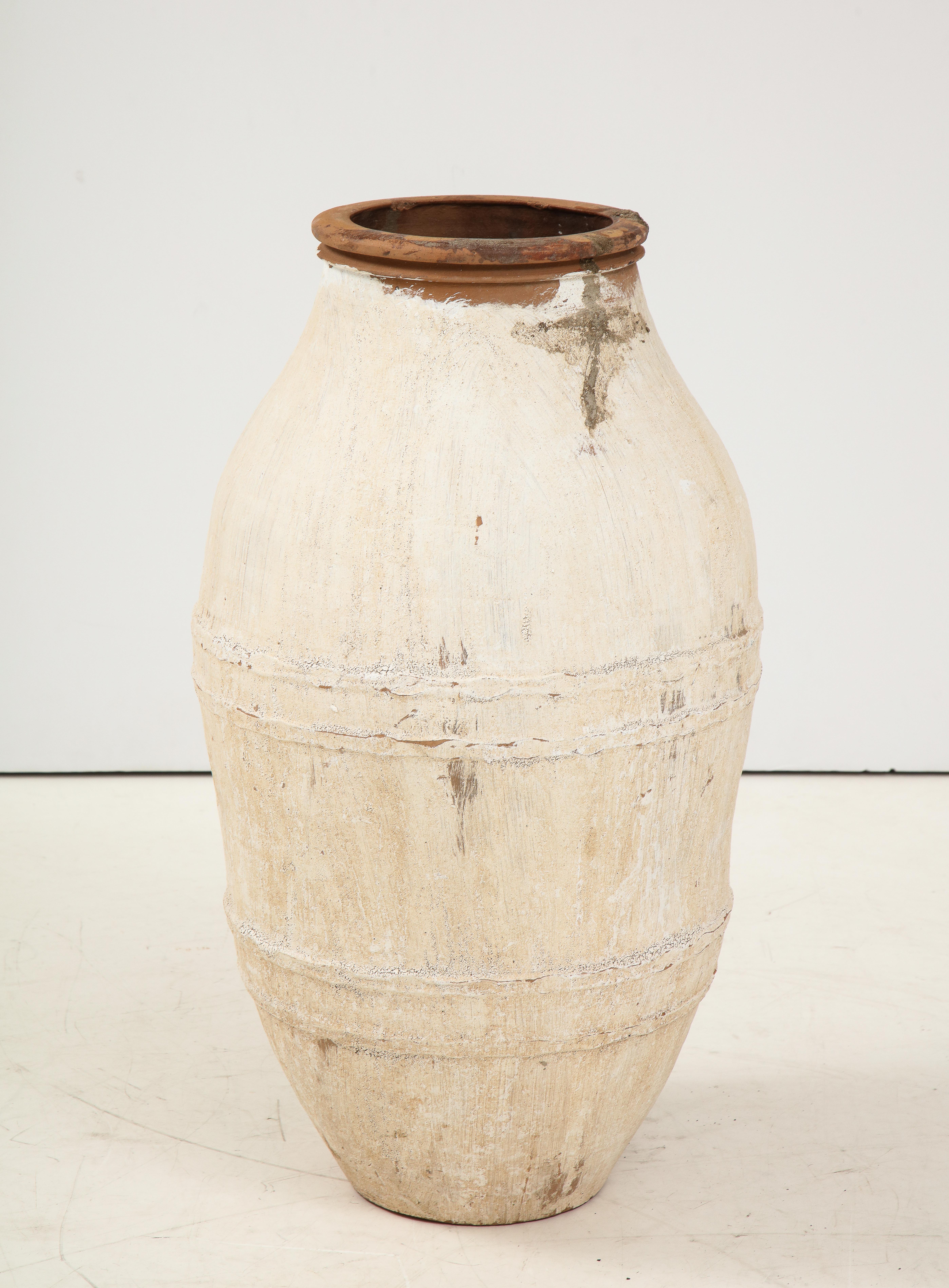 An Italian antique terracotta olive oil jar in white painted finish; with a beautifully aged patina and the natural terracotta showing through. These jars were historically used to transport olive oil in the Mediterranean region during the 18th thru