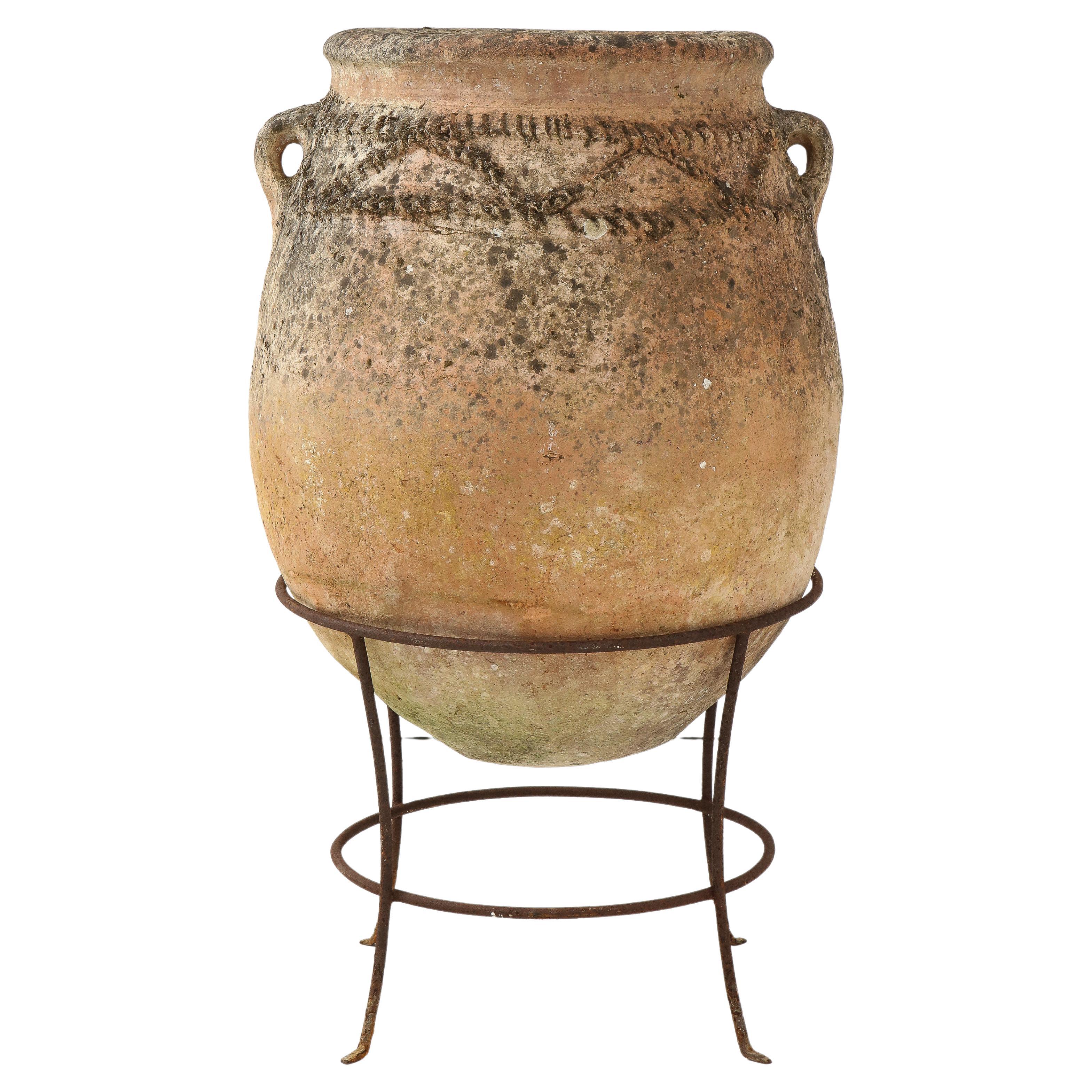 Italienischer antiker Terrakotta-Olivenölkrug auf eisernem Stand