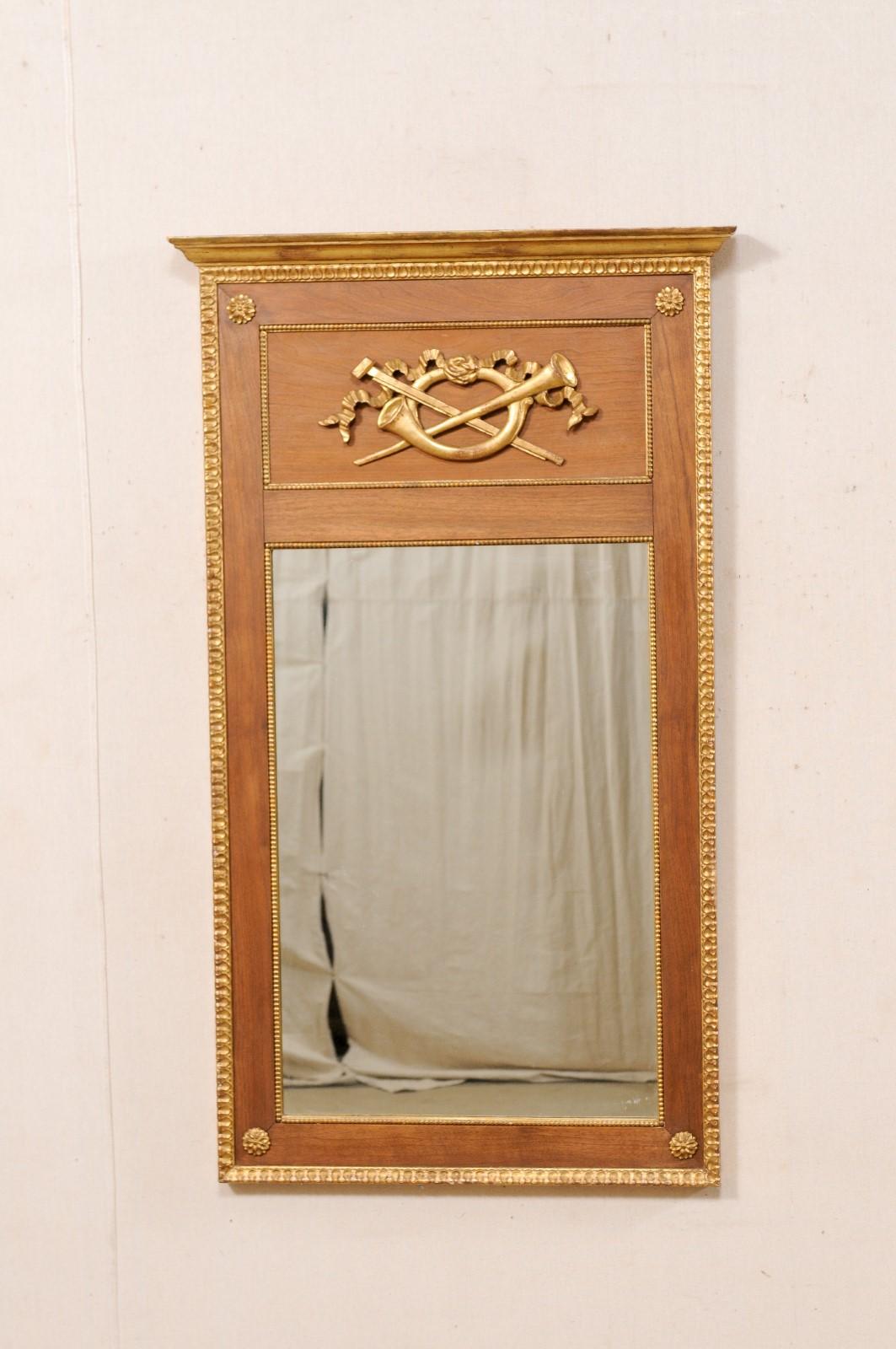 An Italian carved wood wall mirror, with its original gilt finish, from the early 20th century. This antique mirror from Italy is rectangular-shaped, and in typical trumeau fashion, features an upper framed area which is adorn with carved horns in