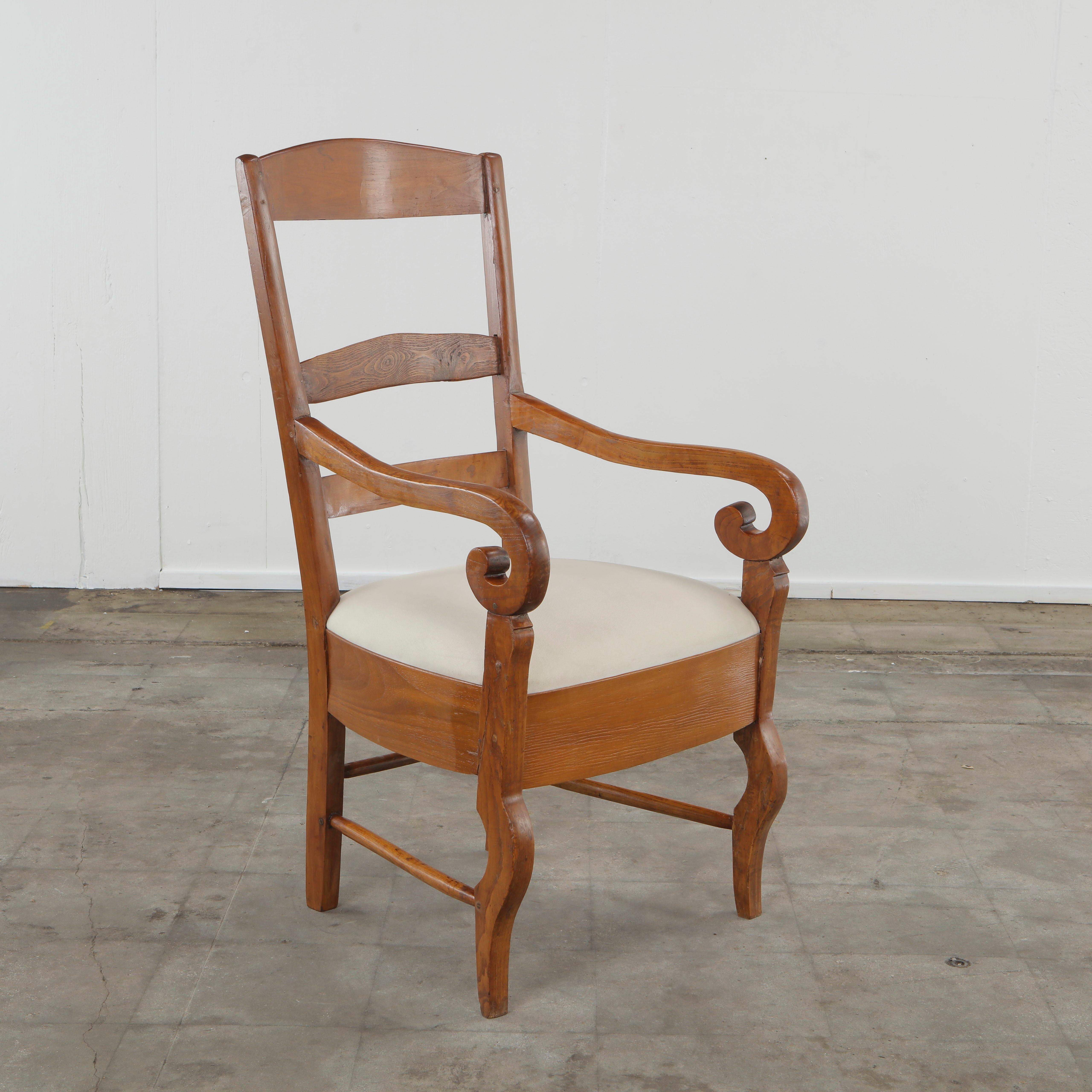 Charming Italian rustic armchair from the 1950s, crafted in solid cherrywood with elegant hand-carved details. The chair features beautifully shaped scroll arms and cabriole-style front legs that give it a graceful, organic profile. The slightly