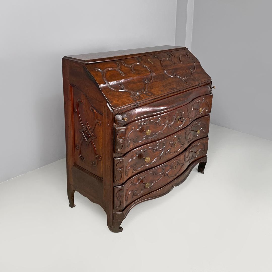 Italian antique wooden chest of drawers with drop-leaf top and decorations 1700s
Wooden chest of drawers with rounded hand-carved decorations. The upper front part has a flap door, which rests on two removable lateral wooden supports, with dividers