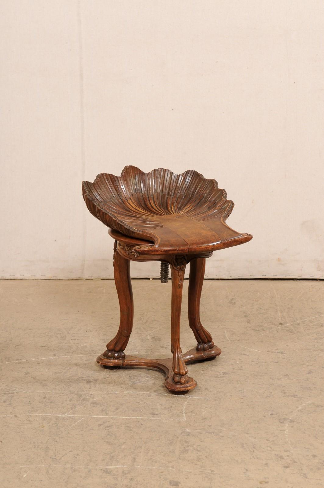 A beautiful Italian Venetian carved-wood grotto chair, with adjustable height, from the turn of the 19th and 20th century. This antique bench from Italy features a fruitwood carved-clam shell seat, atop a rounded apron with swag skirting and
