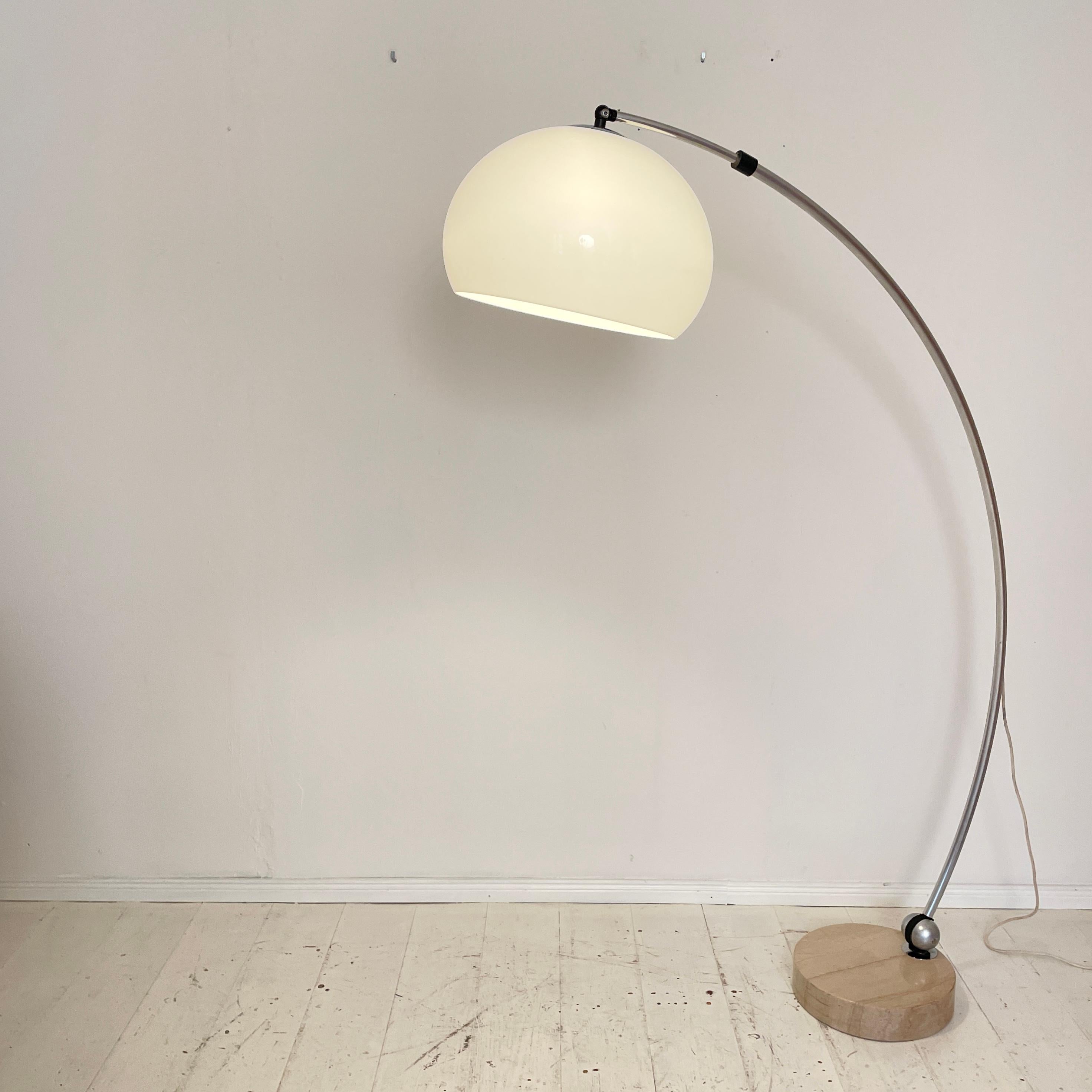 This Italian large arch lamp by Goffredo Reggiani for Guzzini was made in the 1960s. It consisting of a heavy beige travertine stone base with a chrome colored extendable Stand, frosted plastic shade, the arc shaped arm can be rotated on all sides