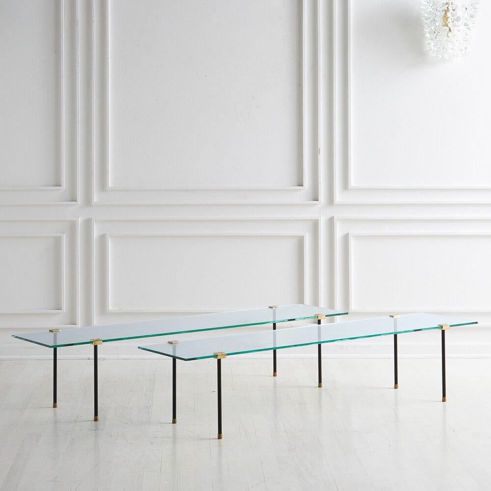 An architectural coffee table featuring black iron legs with a floating glass top resting in brass hardware. Italian, 1970’s. 

Dimensions: 57.5