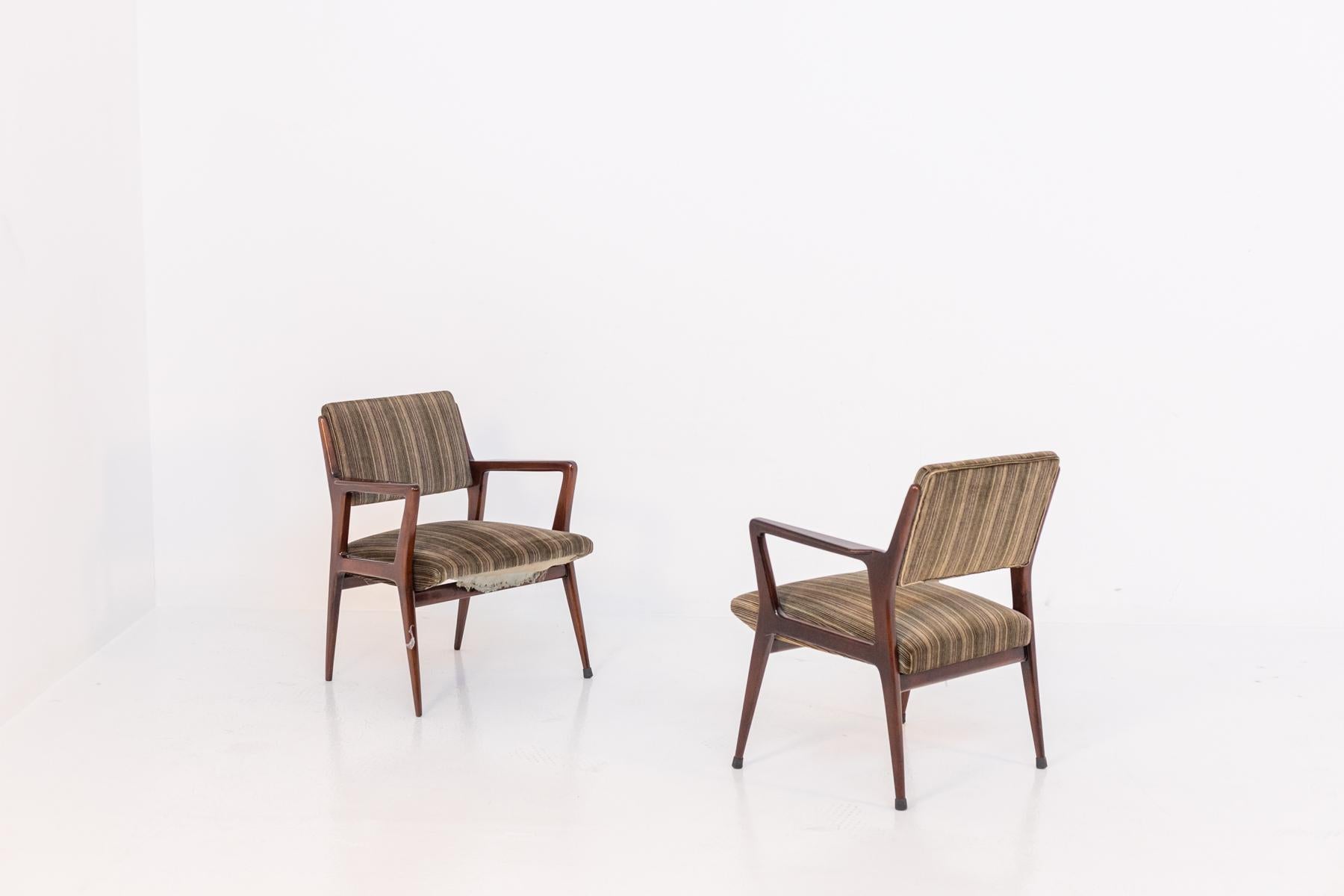 Pair of armchairs attributed to Gio Ponti in walnut wood. The armchairs have the original fabric of the time, a colored corduroy. The armchairs have been restored but have defects in its fabric and slight wear and tear. The pair is perfect to