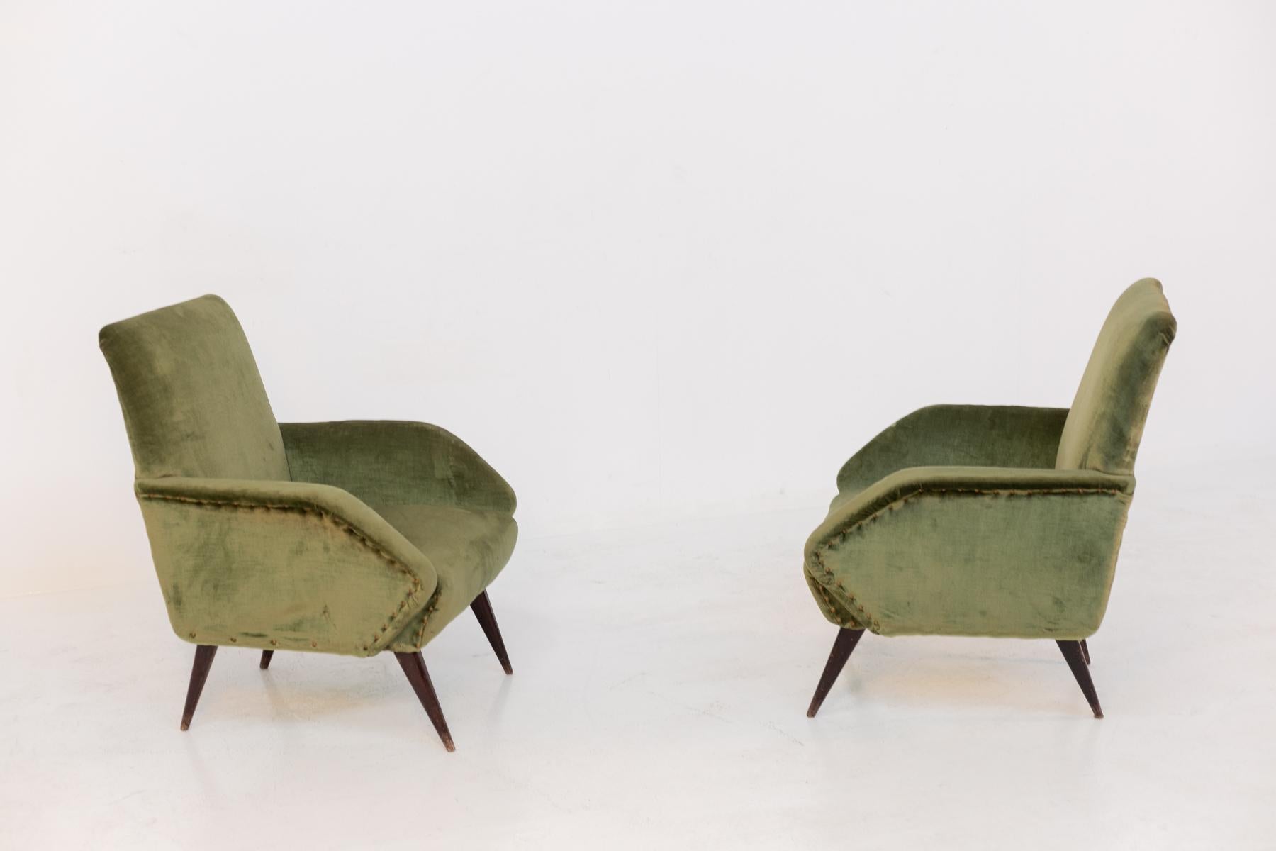 Elegant pair of 1950's Italian armchairs. The armchairs have beautiful geometric shapes that are very sharp and clean. Its armrests are triangular in shape with outward facing tip. To embellish the armchair we find brass studs surrounding the