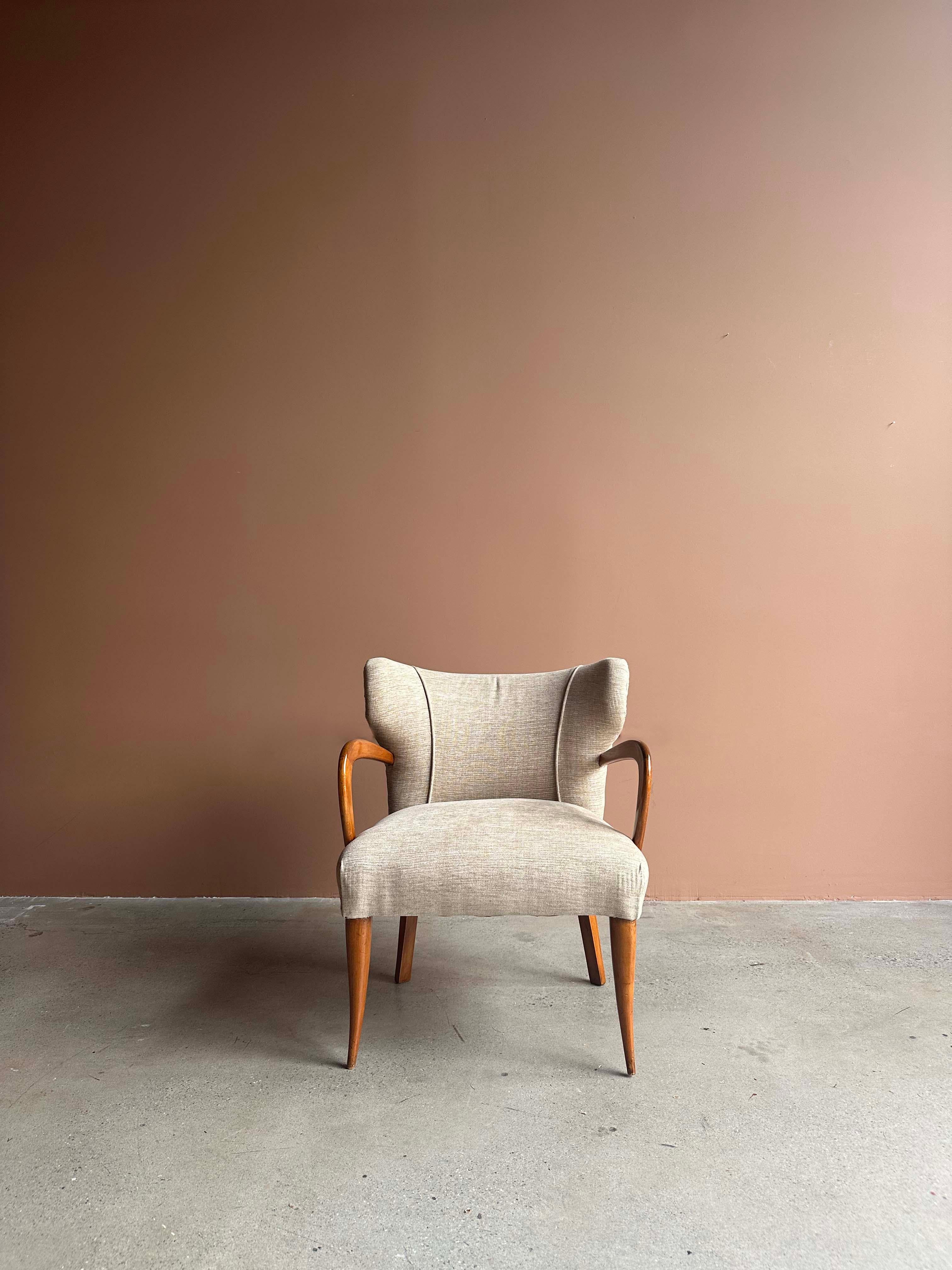 A striking pair of Italian armchairs attributed to the refined modernism of Melchiorre Bega, circa 1940. Sculptural wood arms sweep into tapered legs, balancing the tailored curvature of the tight upholstered backrest. A seamless blend of elegance
