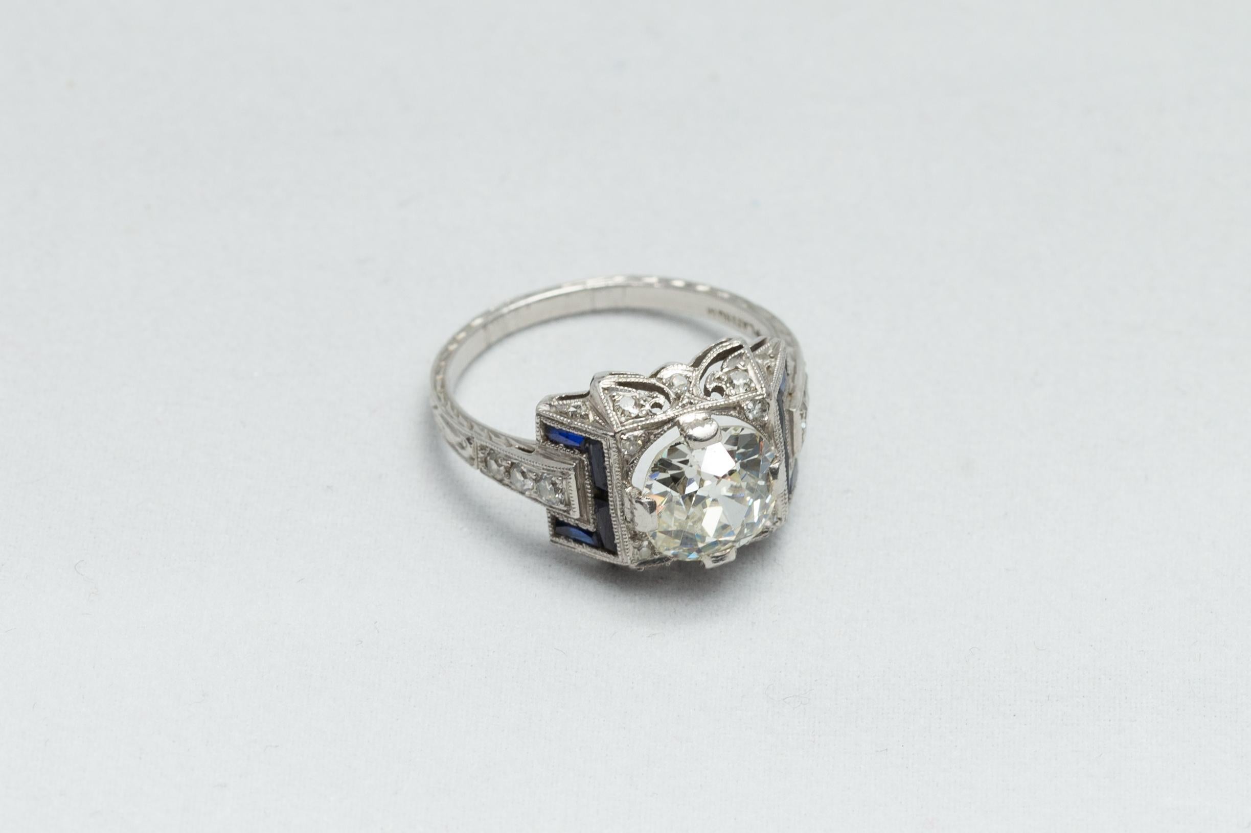 An Italian Art Deco solitaire Diamond ring, set in platinum, flanked with French cut Blue Sapphire, with accent diamonds, circa 1910-1930. Set in an Art Deco platinum mount, this original Art Deco is exquisite and features a central Old European cut