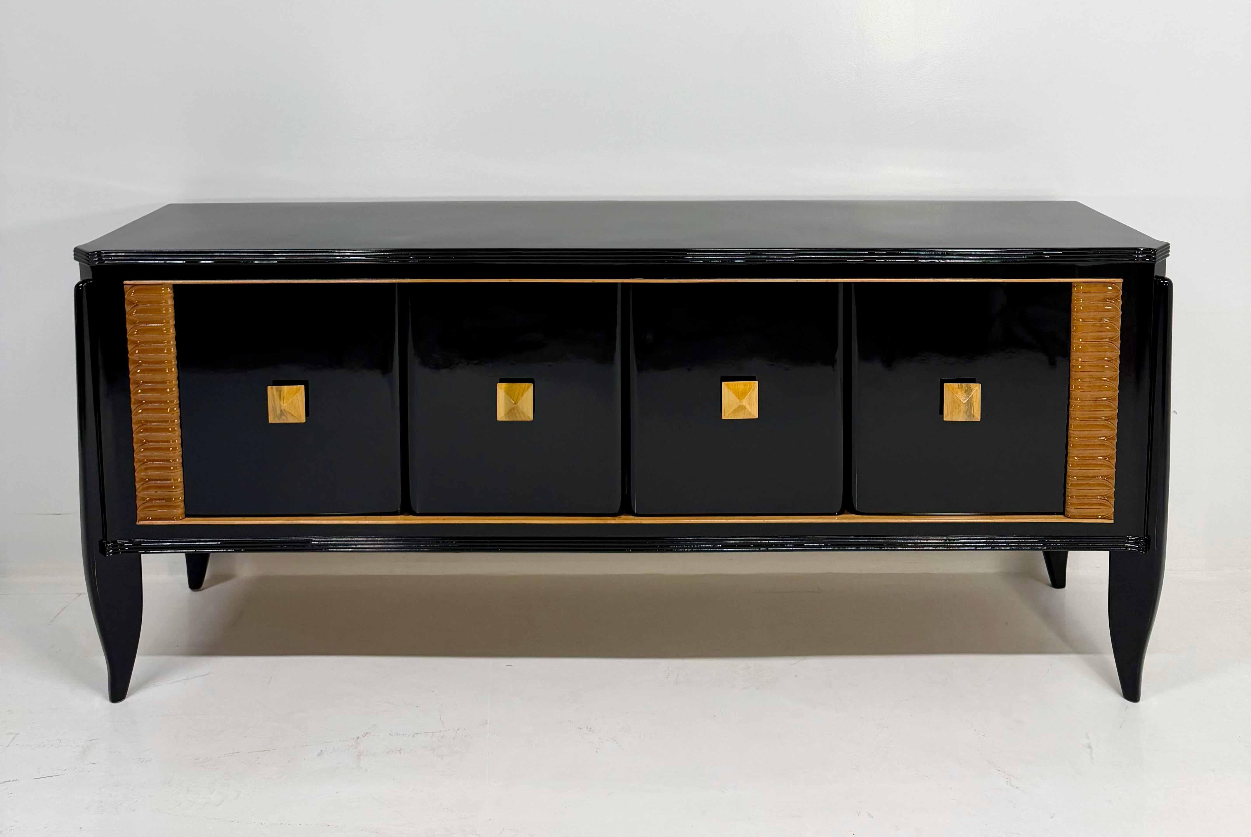 Este elegante aparador italiano se fabricó en la década de 1940 y presenta un refinado acabado ebonizado negro.
El frente muestra cuatro puertas, cada una decorada con perfiles de arce claro y detalles geométricos tallados, que realzan el contraste