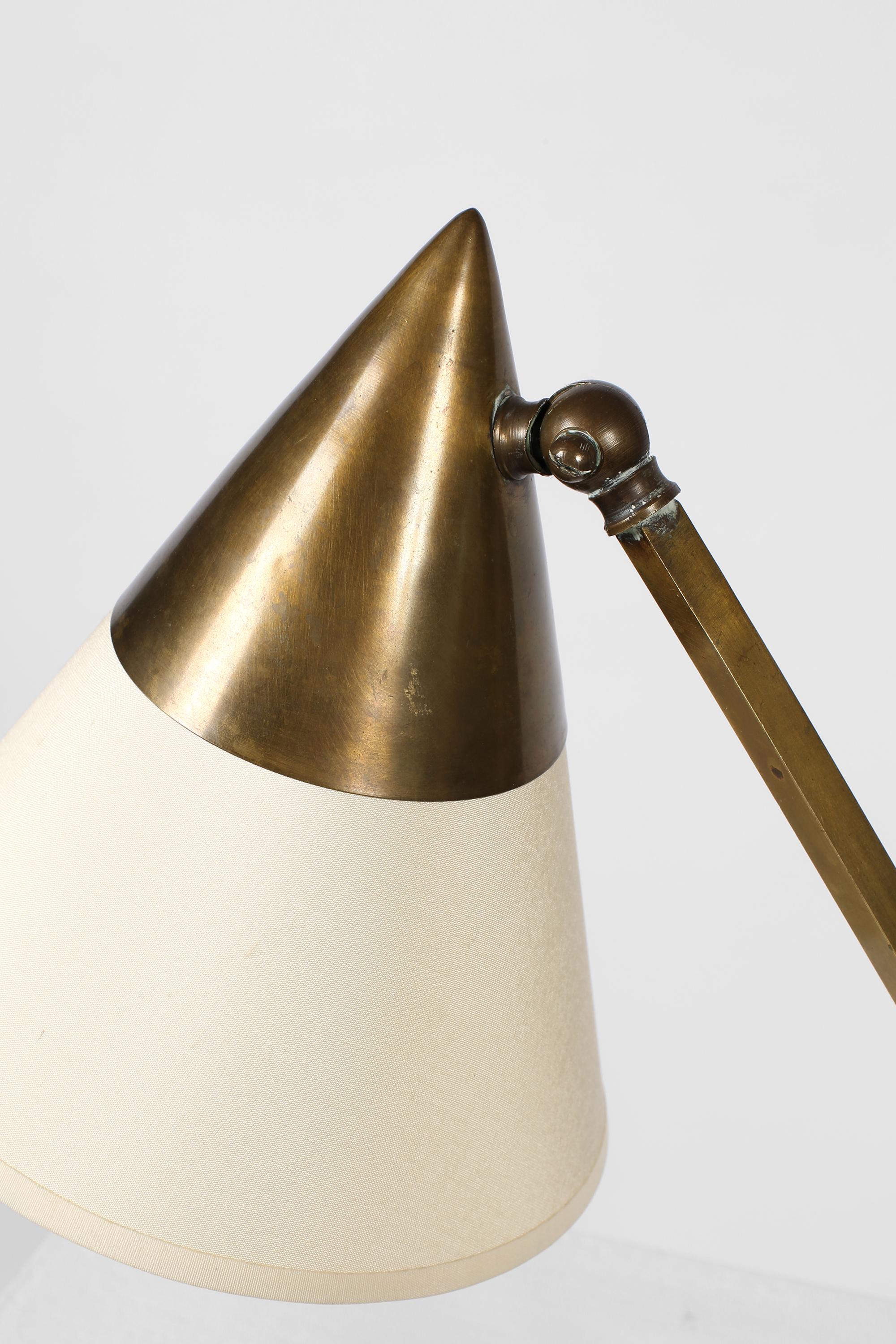 Eine äußerst stilvolle, modernistische Schreibtischlampe aus patiniertem Messing mit einem eingelassenen konischen Schirm, der mit cremefarbener Seide überarbeitet wurde. Verbunden durch einen kantigen Stiel - die Form des Leuchtenkopfes findet sich