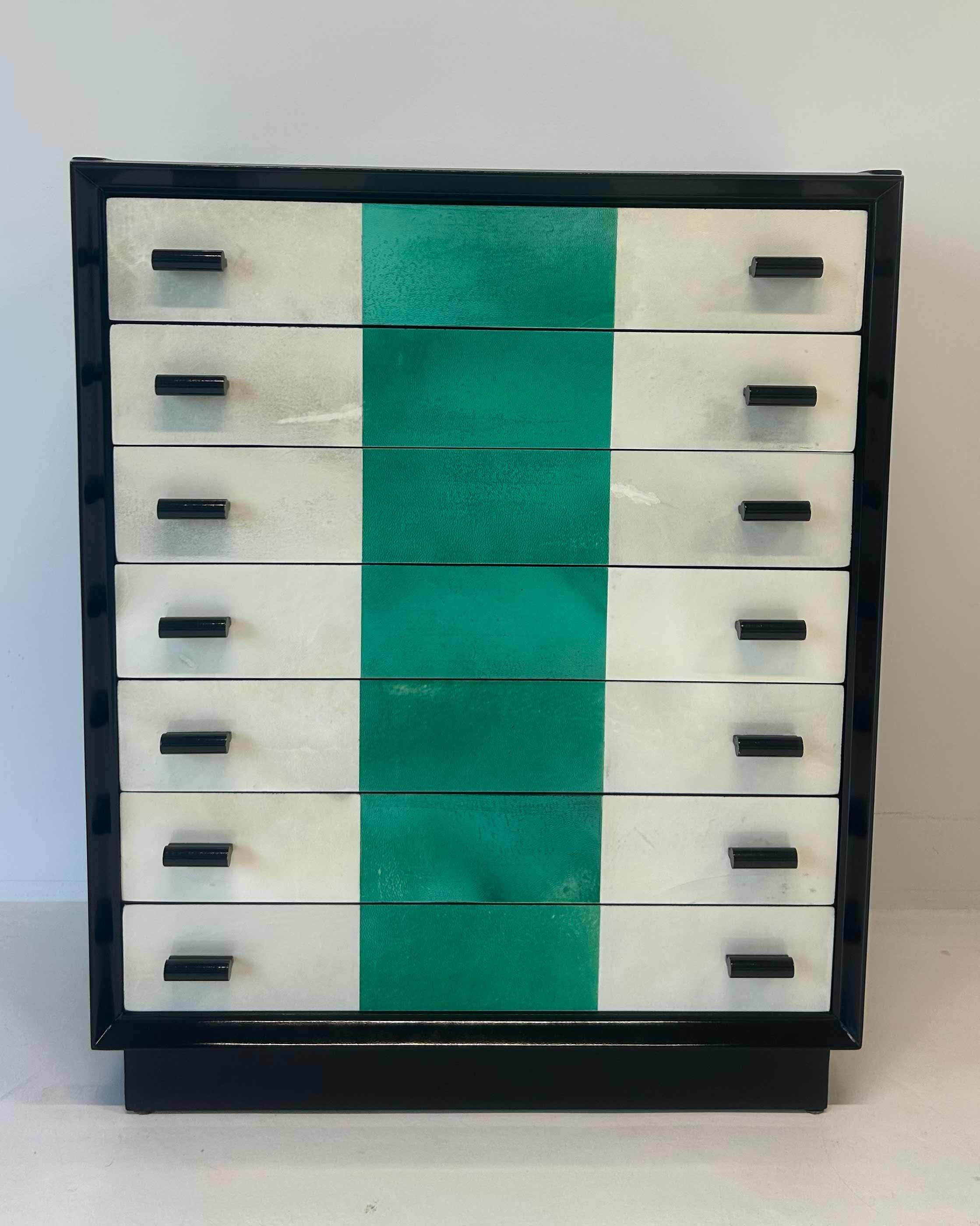 Elégante commode italienne des années 1950, dotée d'une structure raffinée laquée noire. Les façades des tiroirs sont revêtues d'un fin parchemin naturel, rehaussé d'une fine bande centrale en parchemin vert qui apporte une touche distinctive et