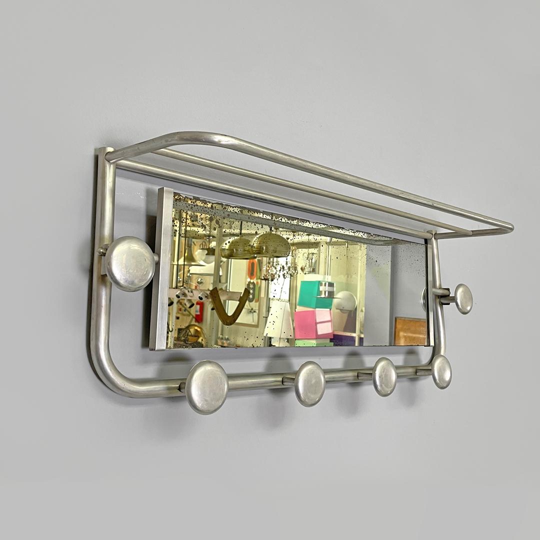 Perchero de pared italiano Art Decó de aluminio con espejo y estante superior, años 40
Perchero de pared con estante. La estructura es de aluminio tubular y tiene seis pomos redondos en total, dos en la parte superior y cuatro en la inferior. En la