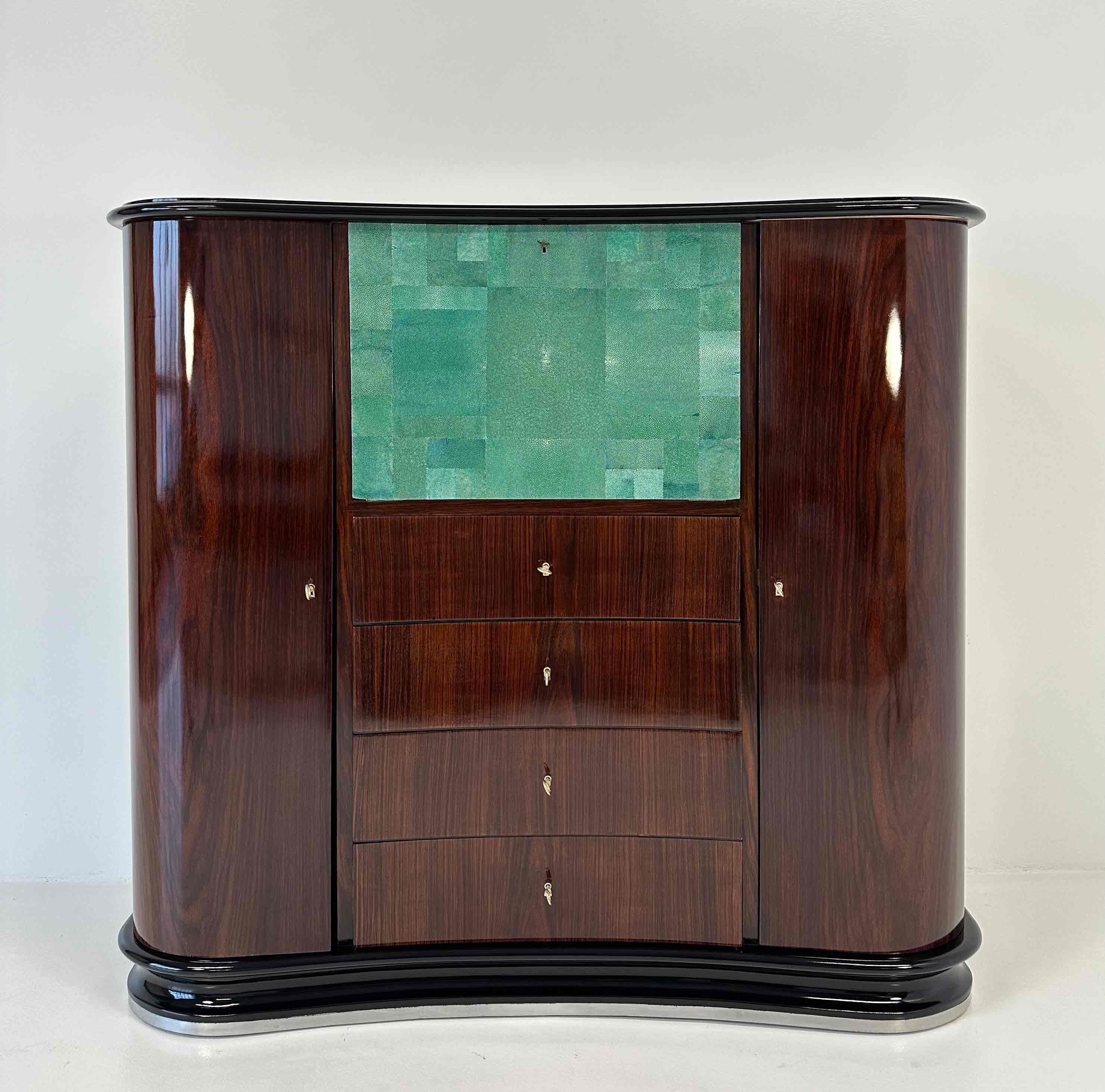 This Art Deco secretaire was produced in Italy in the 1940s and is attributable to Osvaldo Borsani. It is completely in an exotic wood with a black lacquered top and base. The central folding door is covered with aquamarine colored shagreen