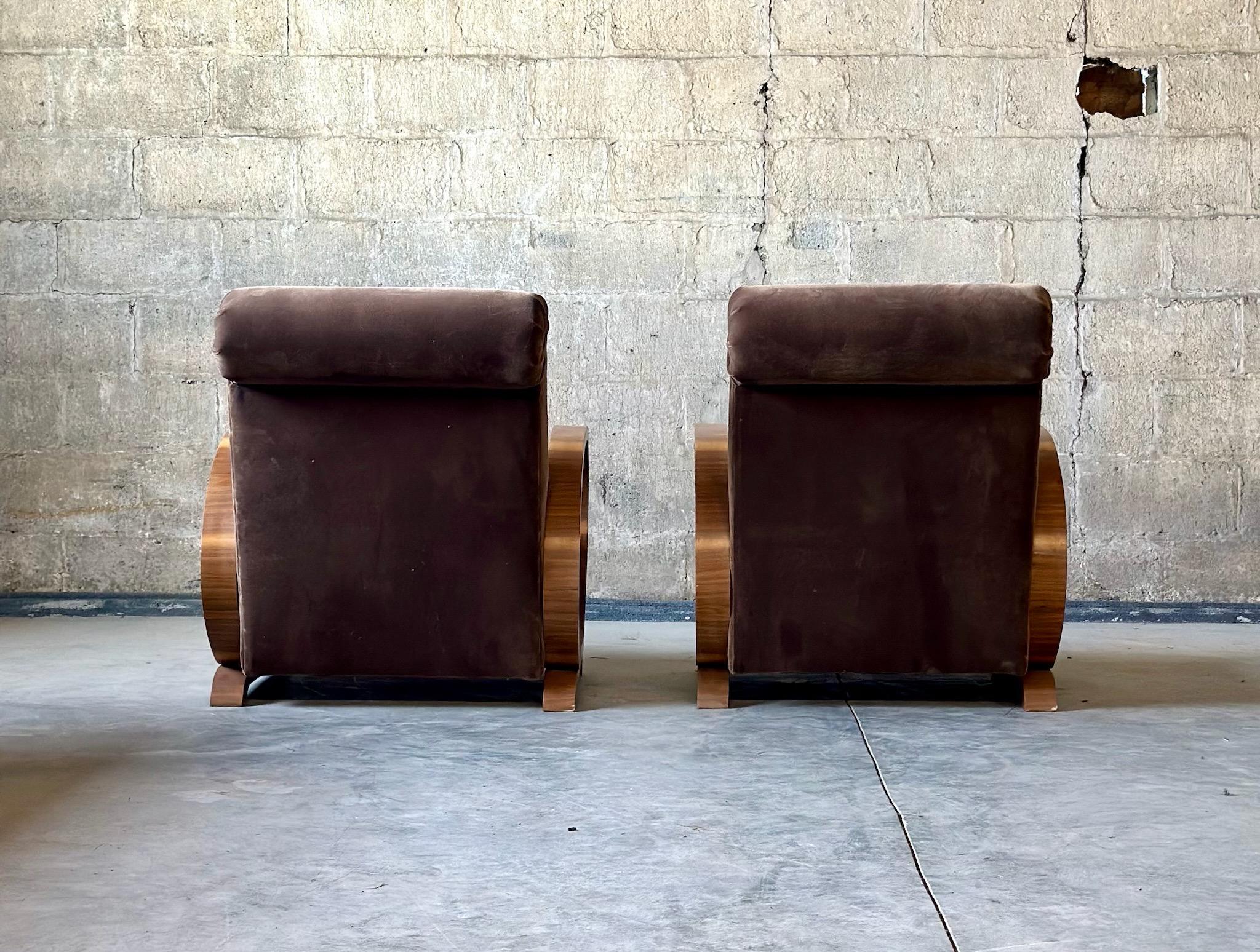 A pair of Art Deco armchairs, circa 1920s. Recently recovered in brown mohair. Beautiful scroll detailing in the upholstery and curved walnut arms make these one of a kind. 
