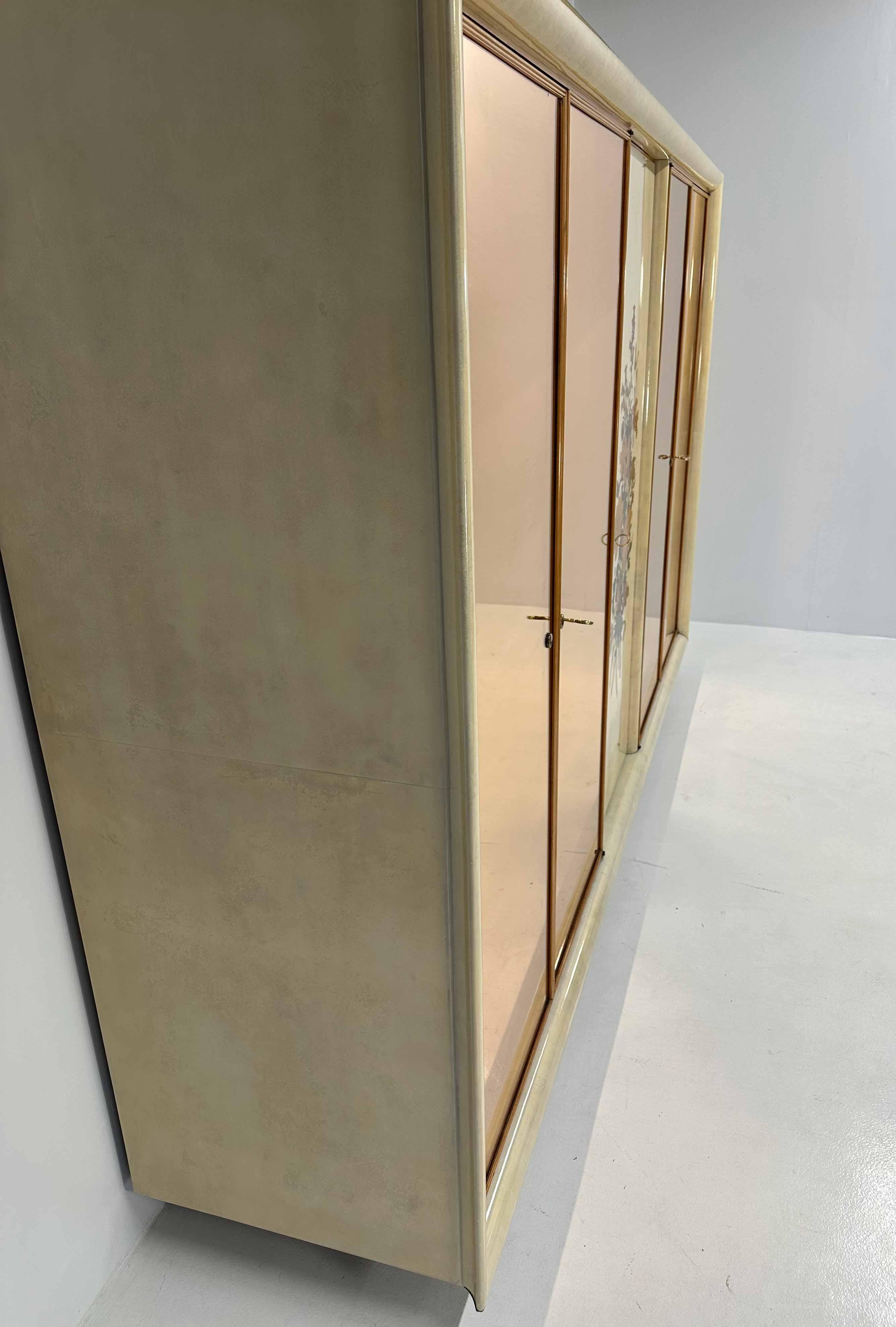 Italian Art Deco five-door Armoire produced around the 1950s in Cantù.
Structure completely covered in parchment, profiles and details in fine maple wood.
The central door features an Anzani inlay with a floral motif designed and produced