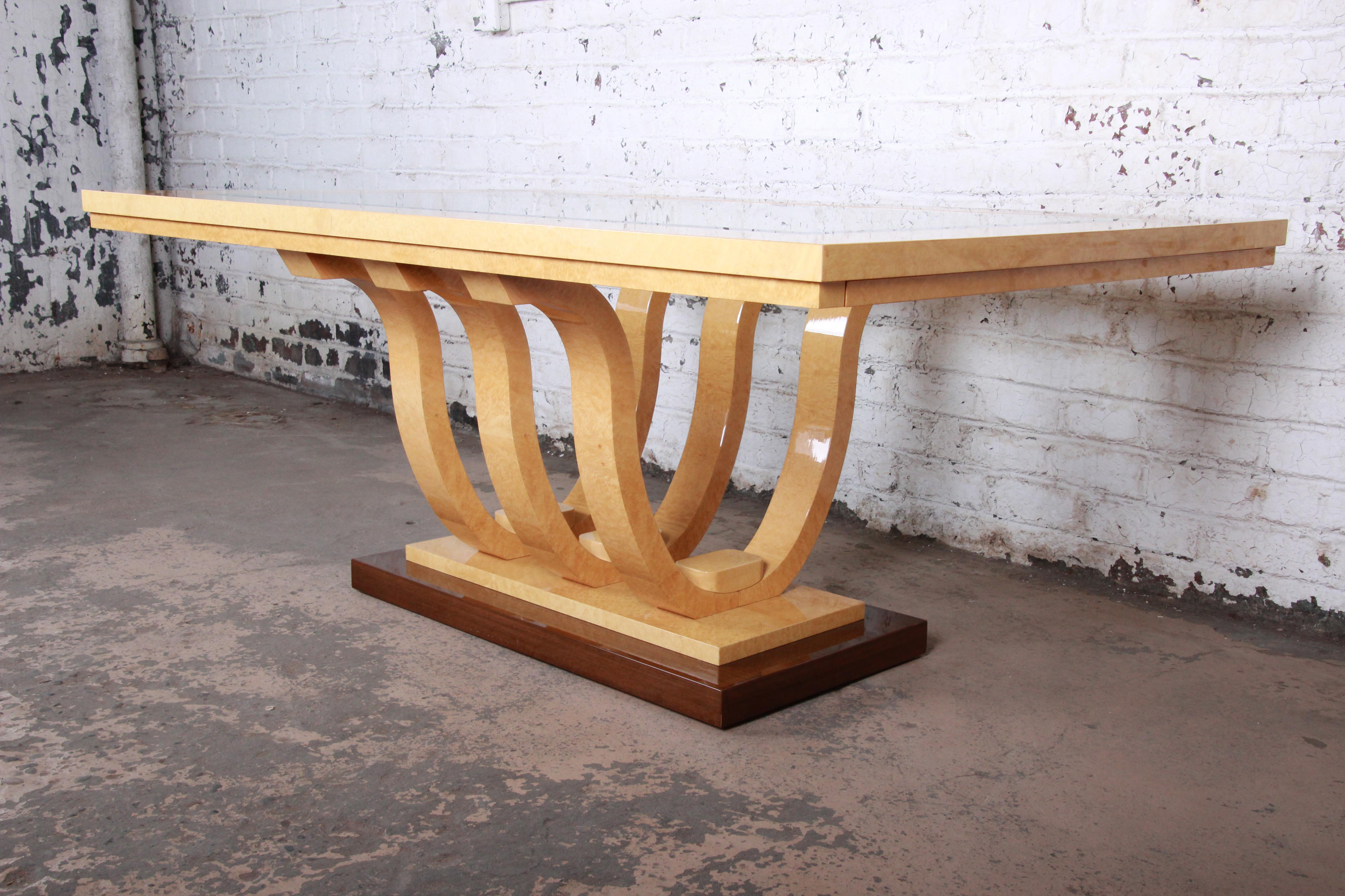 A gorgeous modern Italian Art Deco extension dining table. The table features stunning birdseye maple and mahogany wood grain and a unique sculpted pedestal base. It has two leaves that extend each end of the table. Marked 