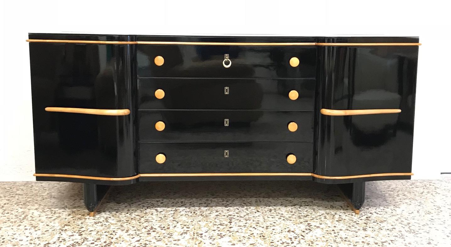 This sideboard was produced in Italy in the 1930s.
The structure is finely lacquered black while the handles the knobs and the profiles are in maple.
Top in black glass.
