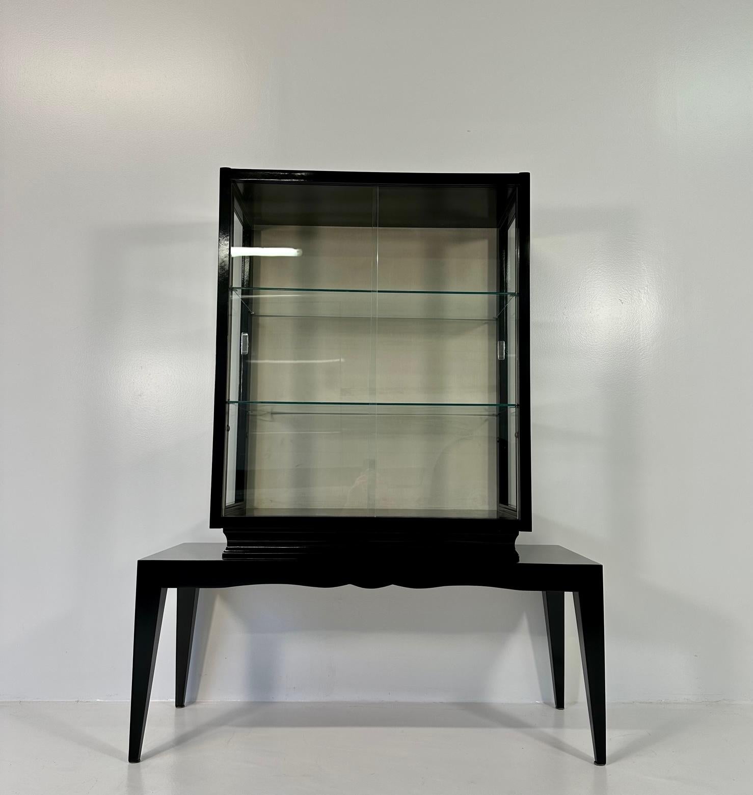 This vitrine was produced in Italy in the 1940s. 
It is composed by a black lacquered structure, glass and a cream colored velvet back. 
Completely restored.