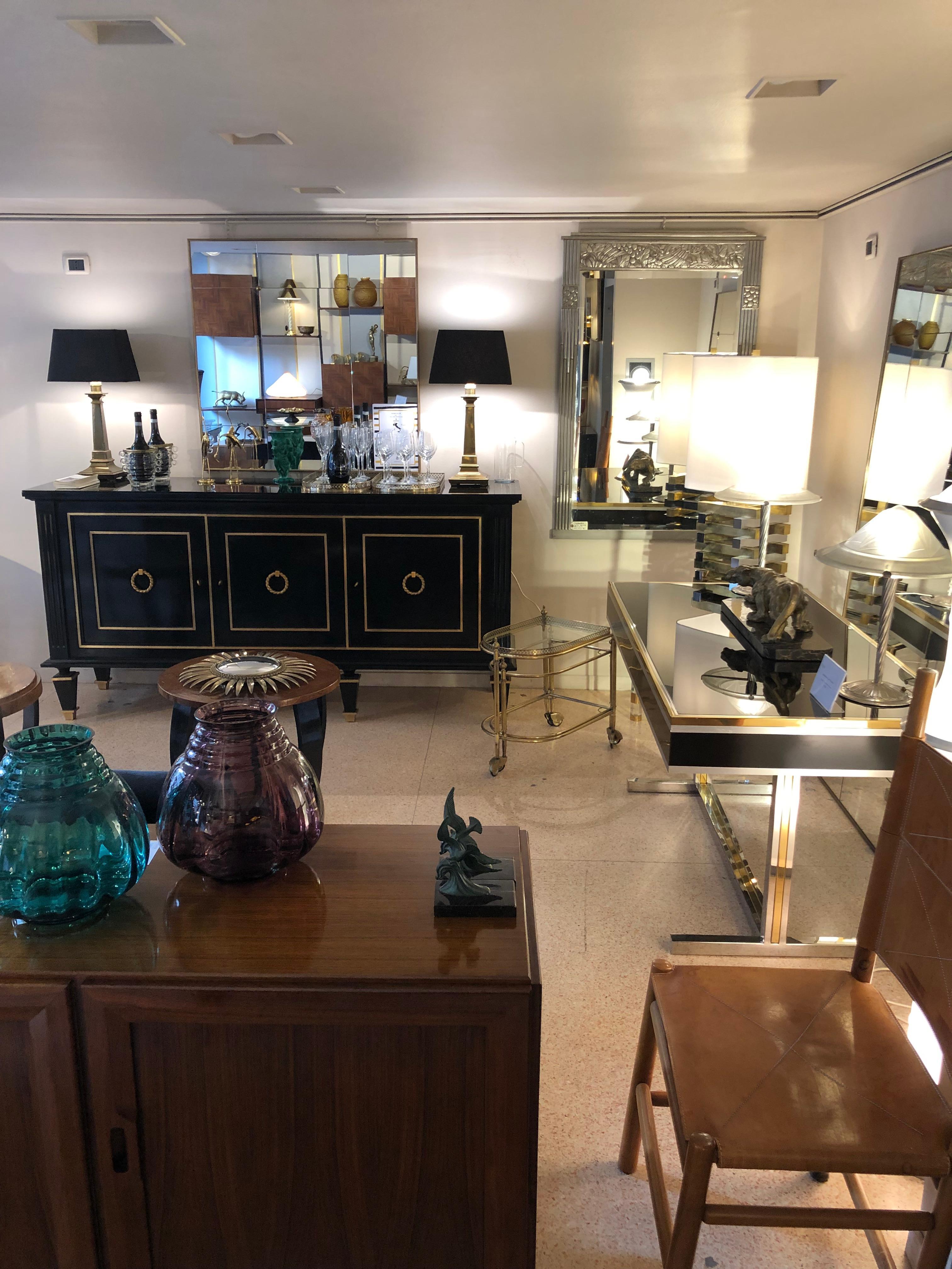 Three doors, black ebonized wood credenza. The central door hides a set of drawers. The other sections are organized with one shelve each. The period of this credenza is 1940s but the style recalls the Louis XVI. Take a look at the details such as