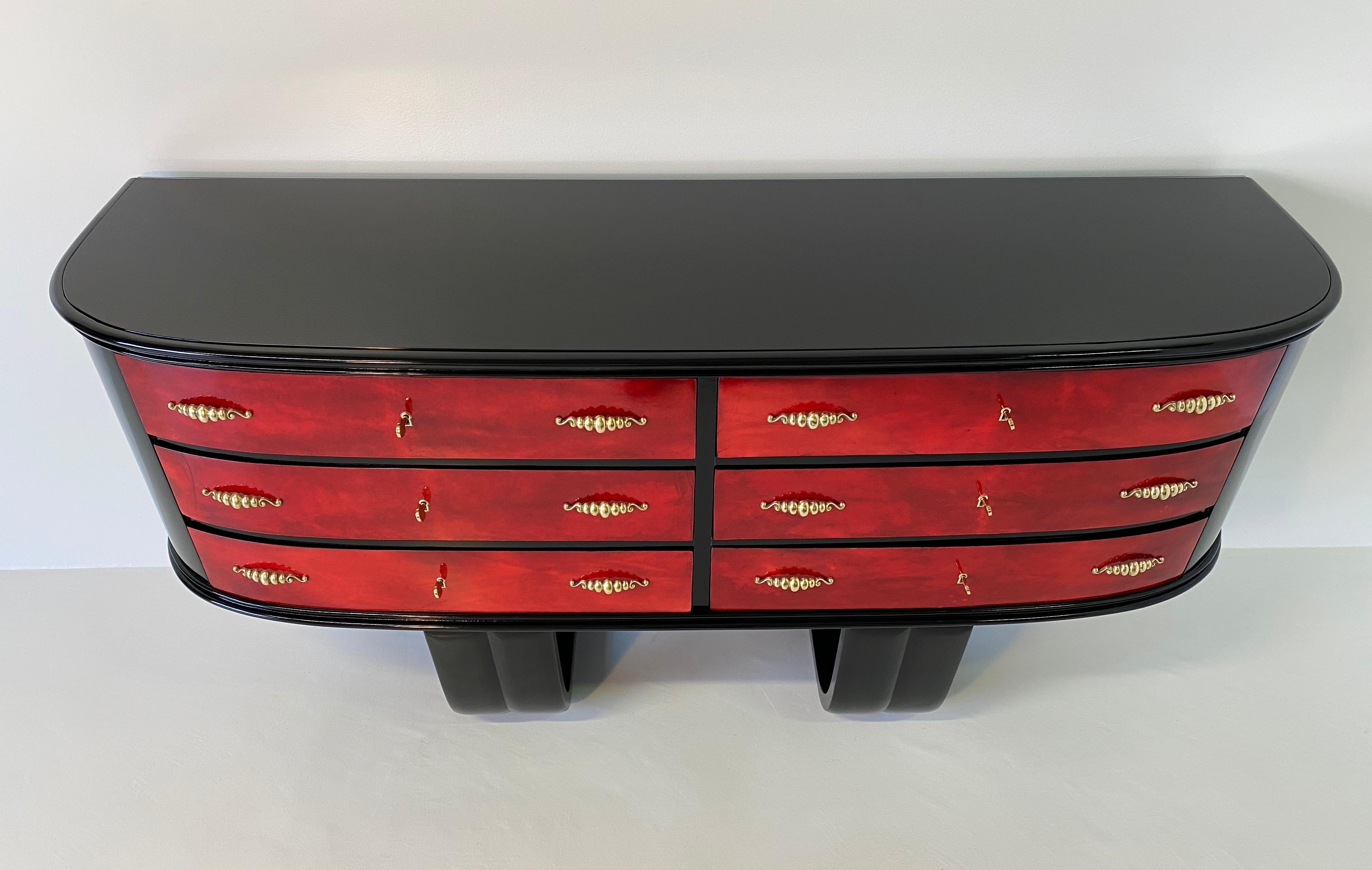 Unique and rare 1950s chest of drawers produced in Italy, 
The structure and legs are in black lacquered wood while the front of the drawers are in cherry red parchment.
The top is in black glass and the handles are in brass.
Completely restored.