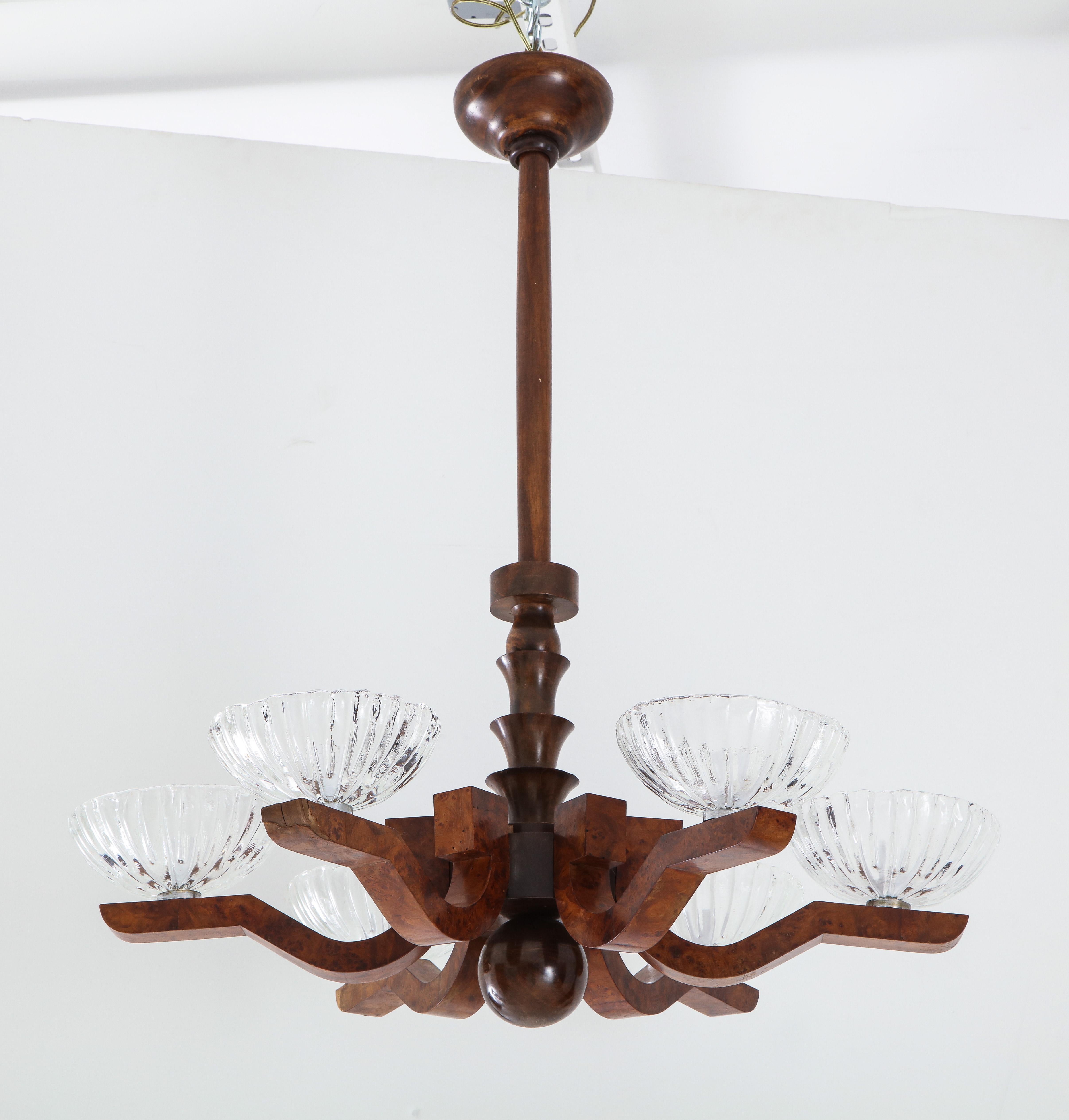 An Italian Art Deco burl wood chandelier; the central stem, canopy, ball finial and six arms in a beautifully carved burl wood veneer with scalloped edged blown glass bobeche. The contrast of the warm wood and glass makes a stunning presentation.