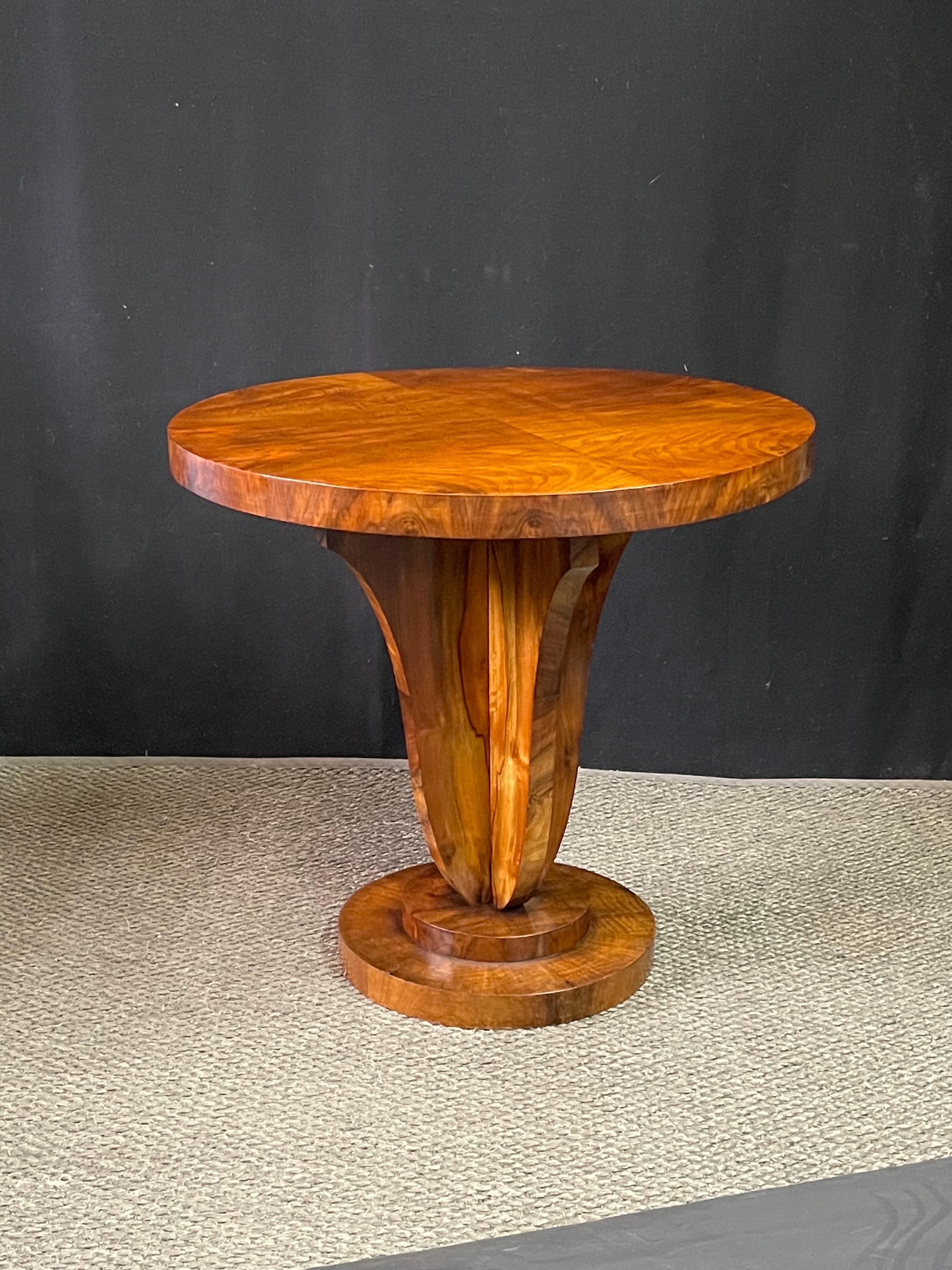 Early 20th century Italian side table of beautifully burled walnut made during the Art Deco period. A thick round table top is veneered in a book-matched walnut and rests on a winged pedestal that elegantly tapers to a two tier platform base. The