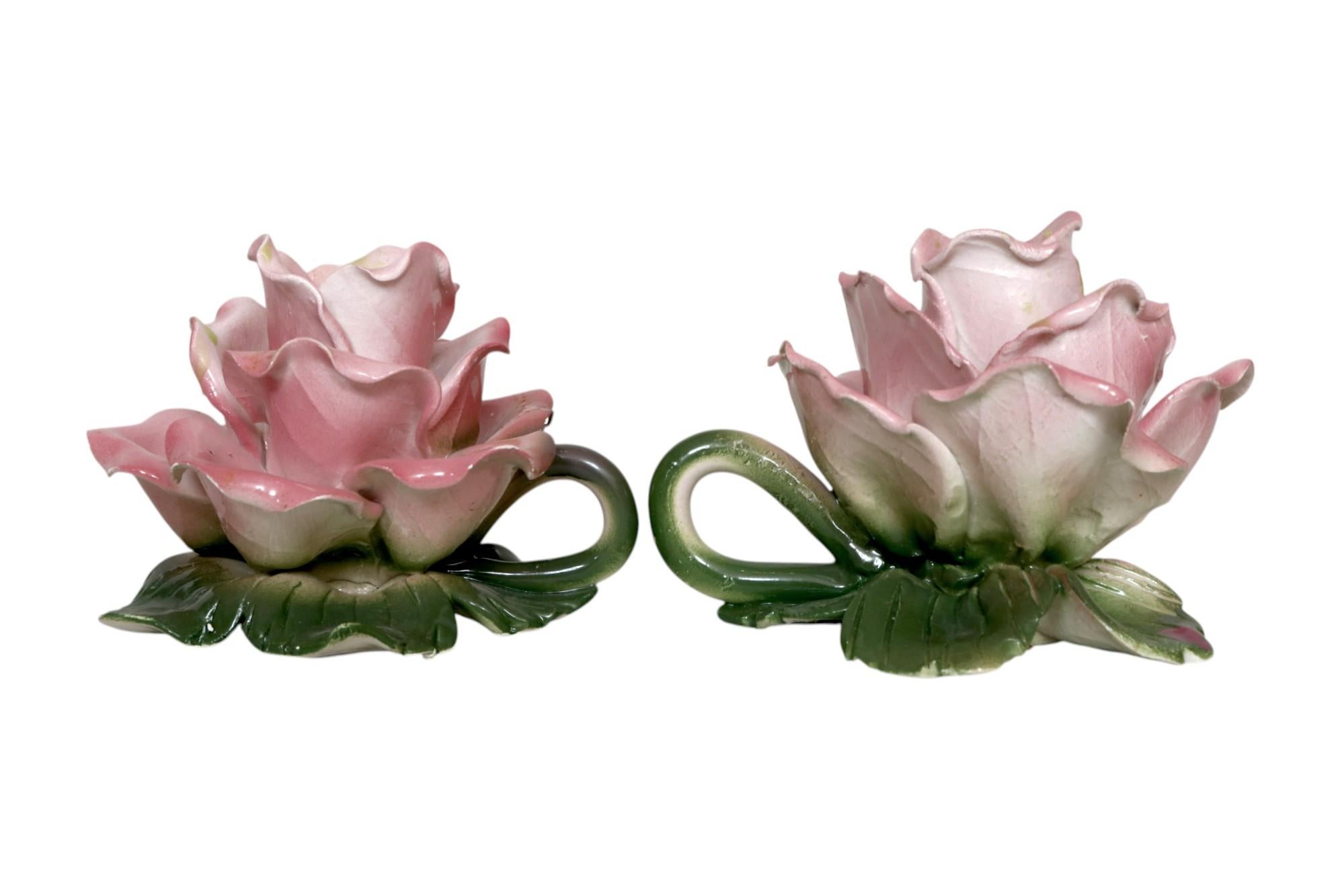 Paire de bougeoirs de chambre italiens d'époque Art déco. En céramique et en forme de roses, avec des pétales roses superposés et délicatement enroulés sur une base de feuilles vertes. Chacun a une poignée en forme de goutte d'eau. Marqué en dessous