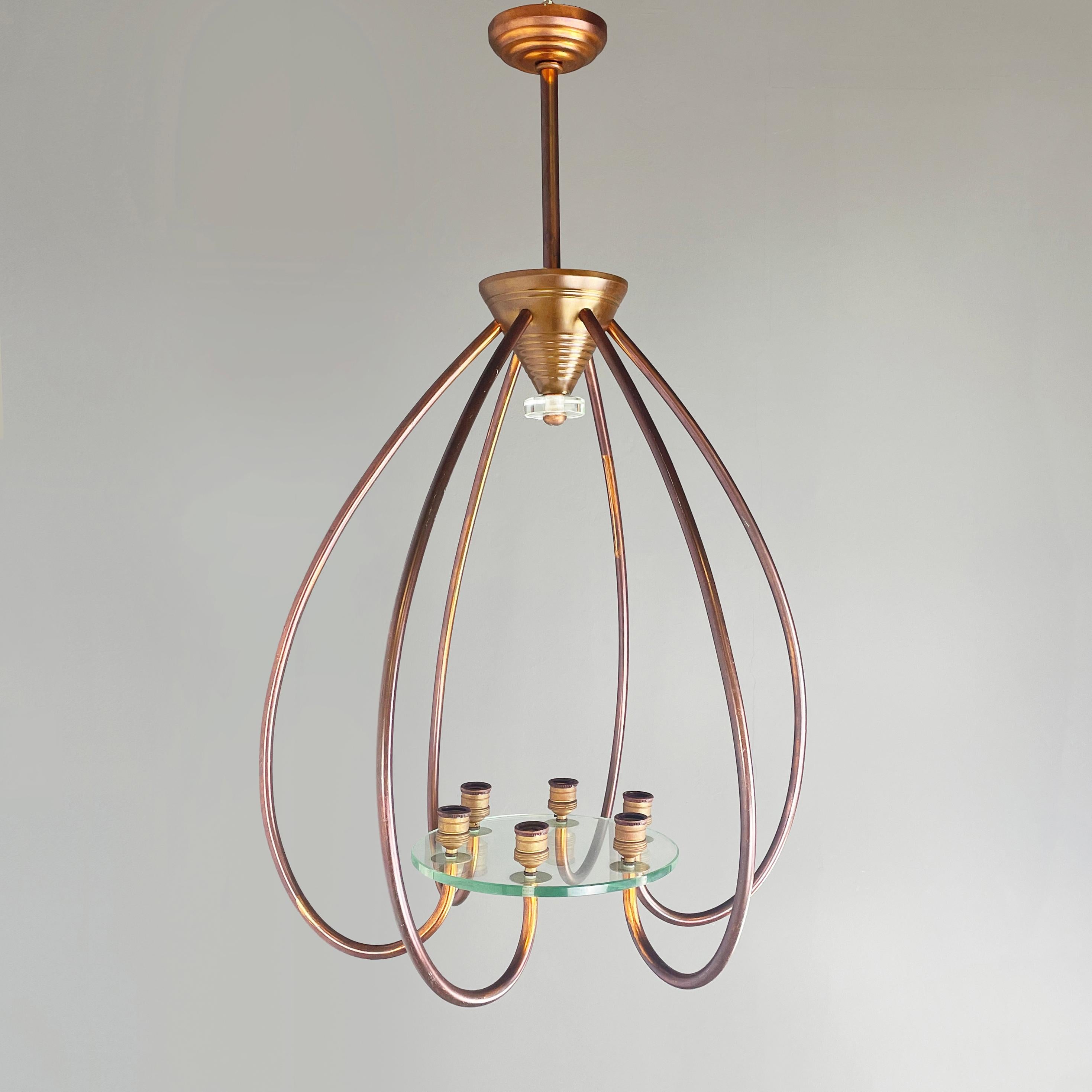 Italian art deco Chandelier with six light in copper and glass, 1940s.
Chandelier composed of 6 inwardly curved arms in burnished copper rod. The arms are joined in the center by a thick round glass plate, on which the 6 light sources are placed.