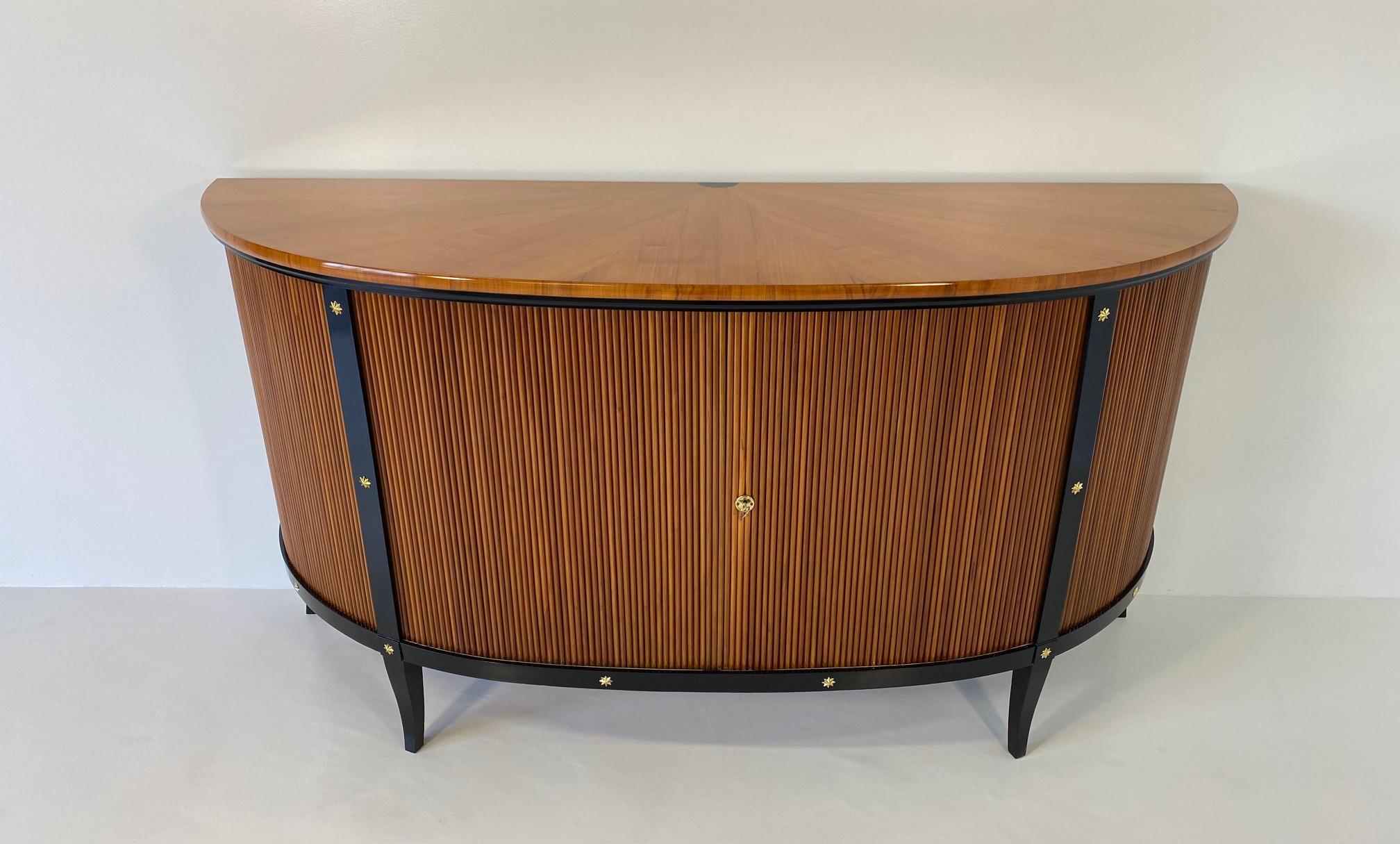 This Art Deco style sideboard was produced in the late 1950s in Italy. It is entirely made of cherry wood and has black lacquer profiles and decorations.
The sideboard features sliding doors that gets hidden inside the sideboard once opened. 
The