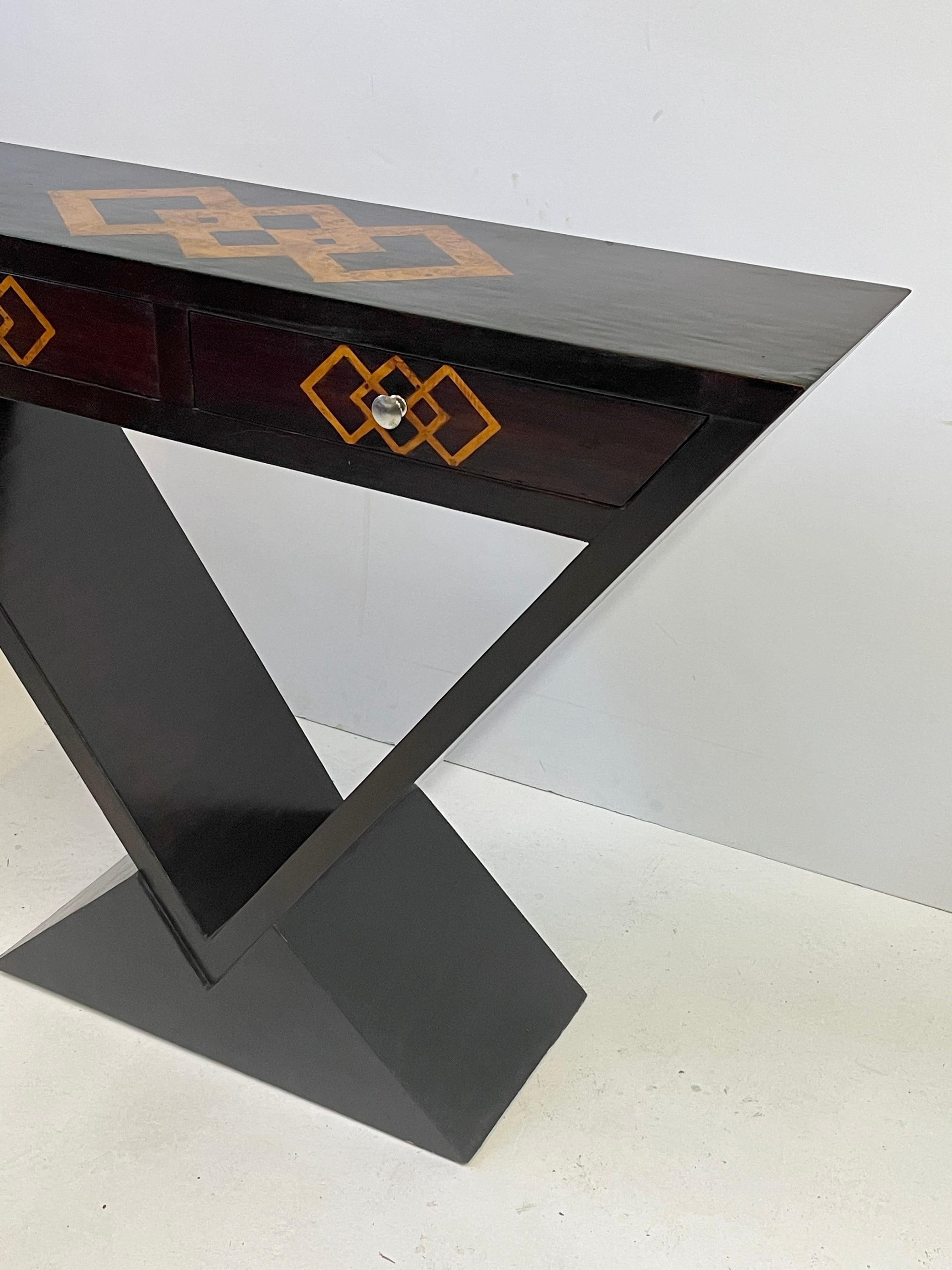 20th Century Italian inlaid console in the style of Art Deco. The table’s top is beautifully inlaid with burlwood in diamond patterns and holds matching drawers in its frieze. The case has an inverted pyramid shape and rests on a triangular platform